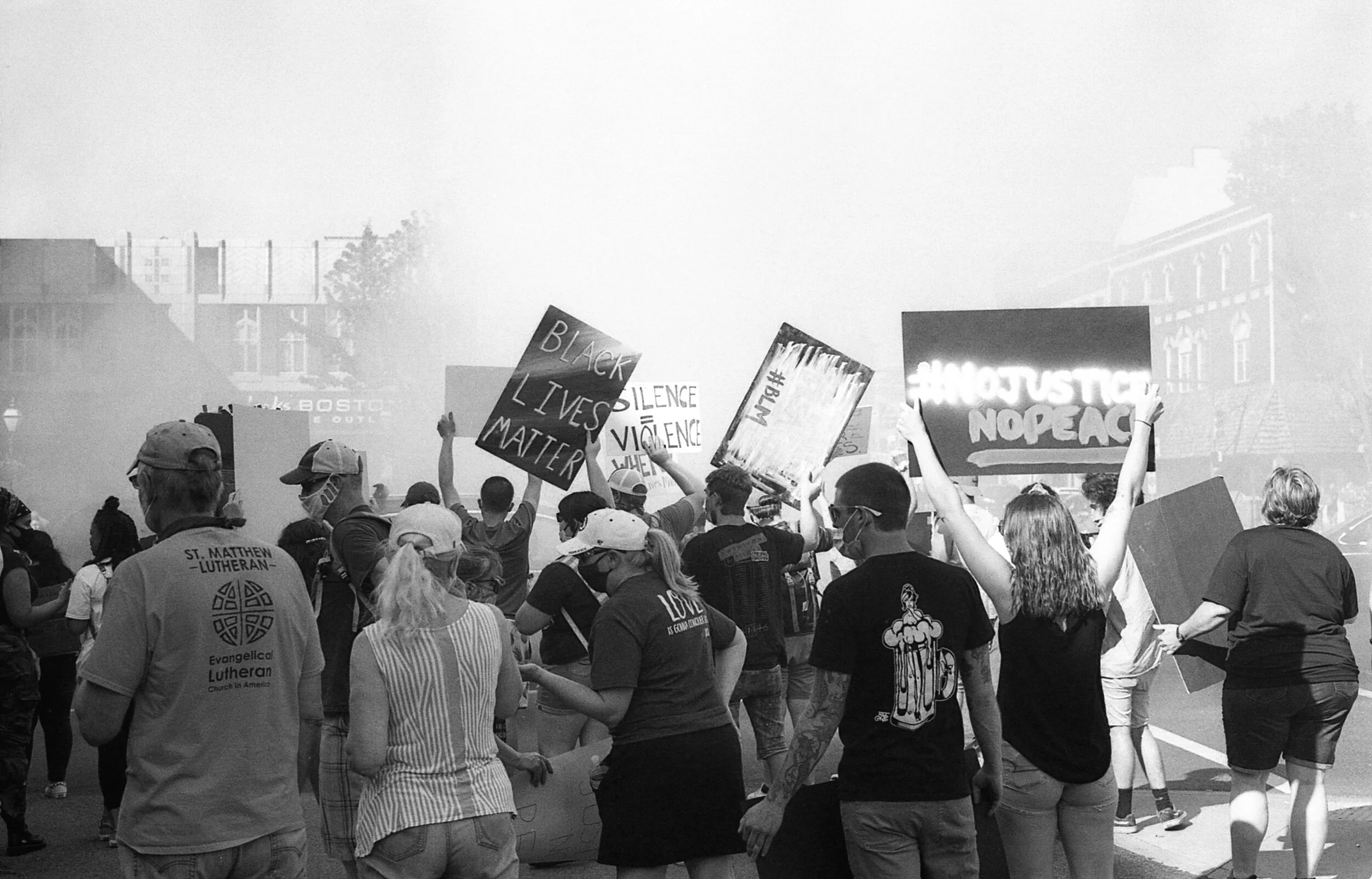 Black and white photo of a protest with people holding signs including "Black Lives Matter" and "No Justice, No Peace."