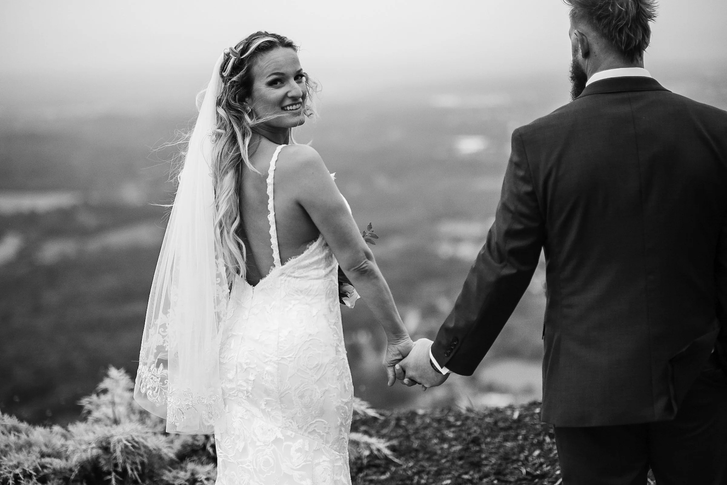 bride and groom holding hands atop mountain at The Hidden Hill wedding venue by Charlotte photographer Brandon Pickett