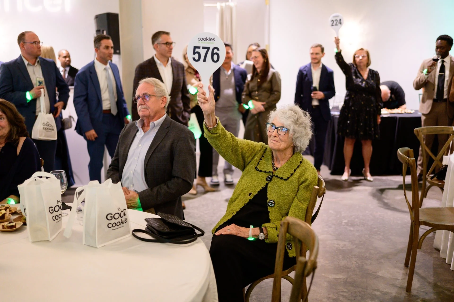 woman holding up paddle at Cookies For Kids Cancer event at The CaseyBy Charlotte photographer, Brandon Pickett.