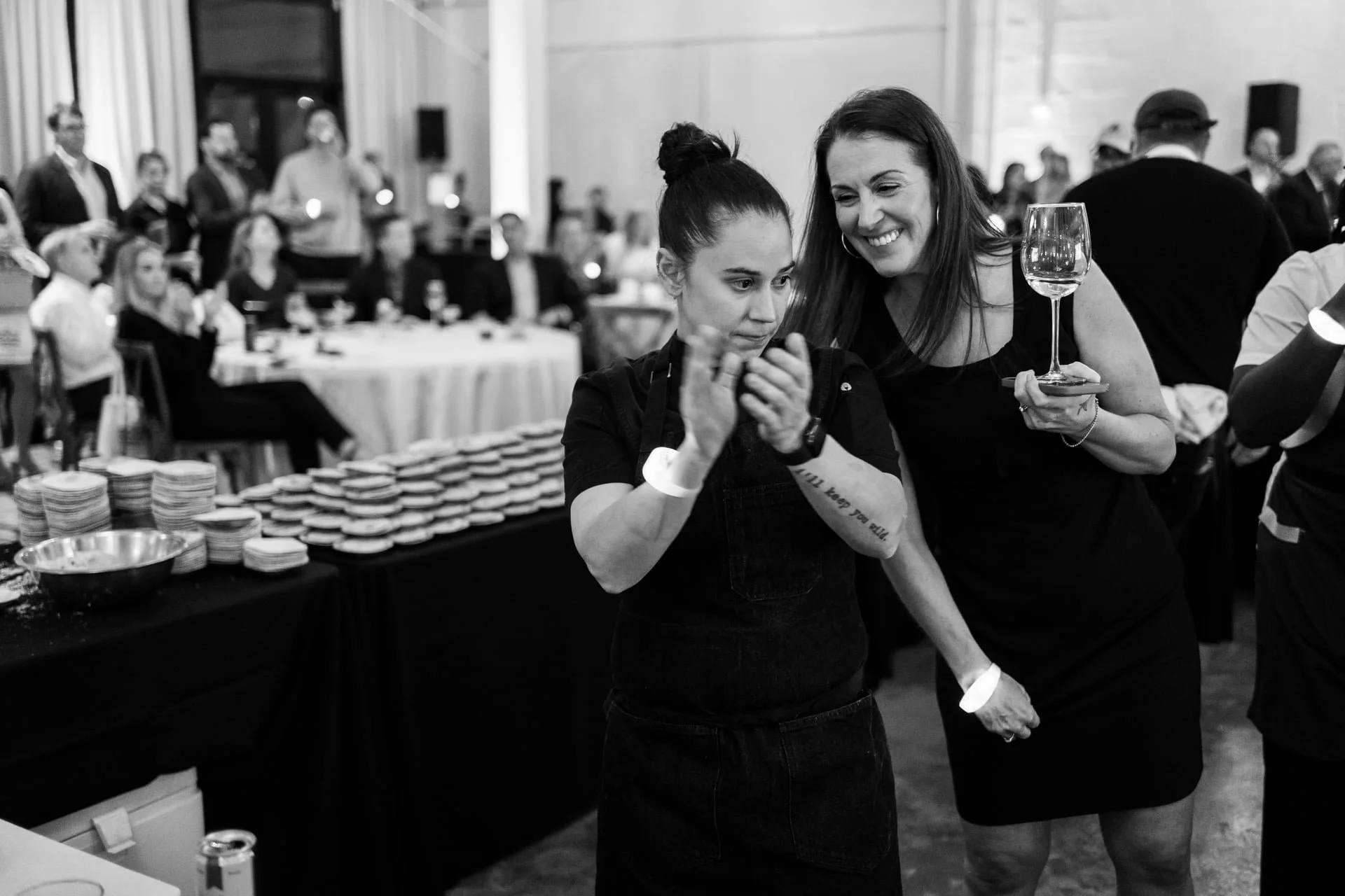 woman holding a wine glass shares a laugh with her friend during Cookies For Kids Cancer event at the Casey in Charlotte