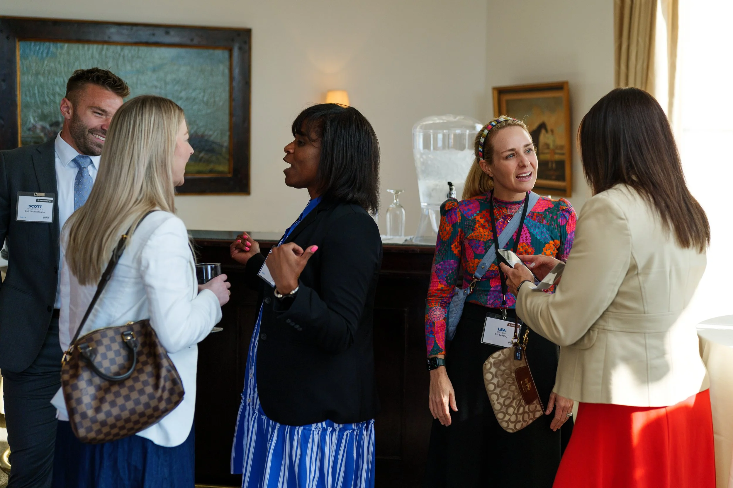 Four women and one man engaged in conversation at the orbie awards in charlotte in a well-lit room by brandon pickett photography