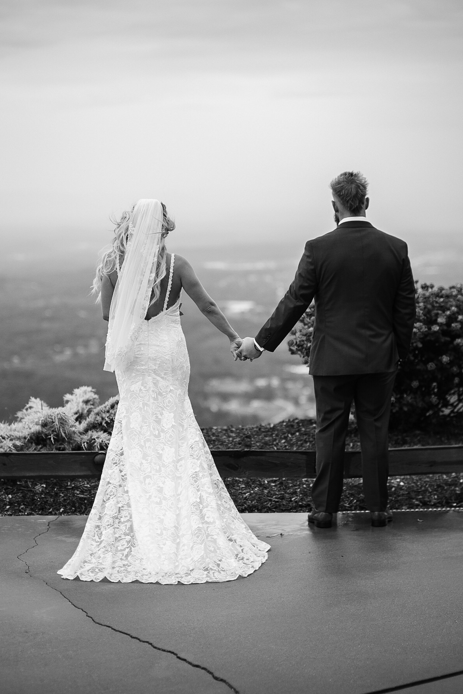 bride and groom holding hands looking out at the mountains at The Hidden Hill wedding venue. Photo by Brandon Pickett Photography