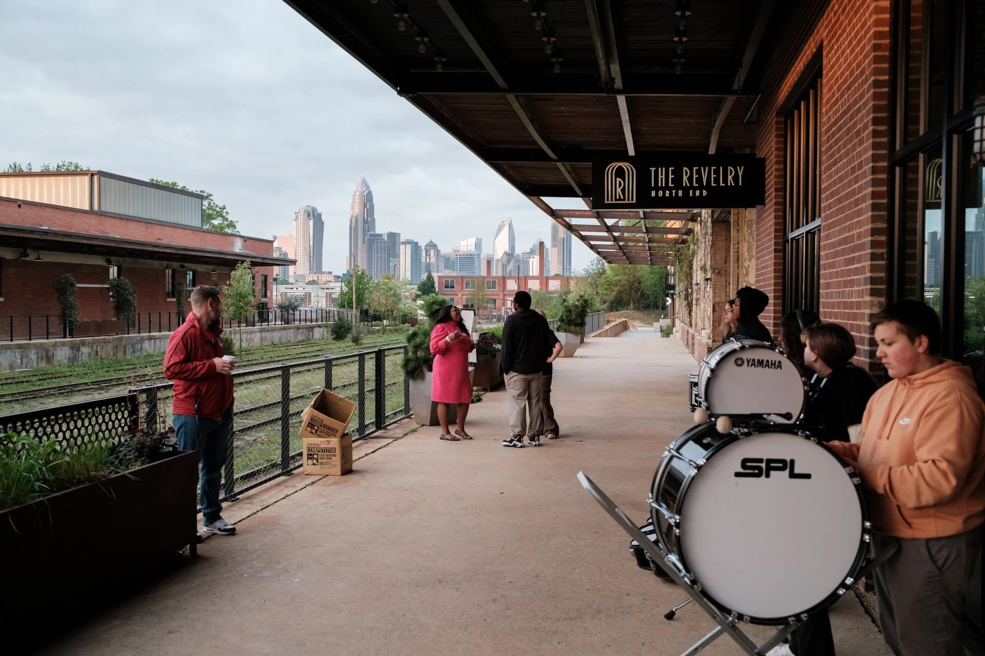 event photo at The Revelry  for Teach For America at Camp North End, Charlotte. Photo shows a high school marching band with the Charlotte city skyline in the background