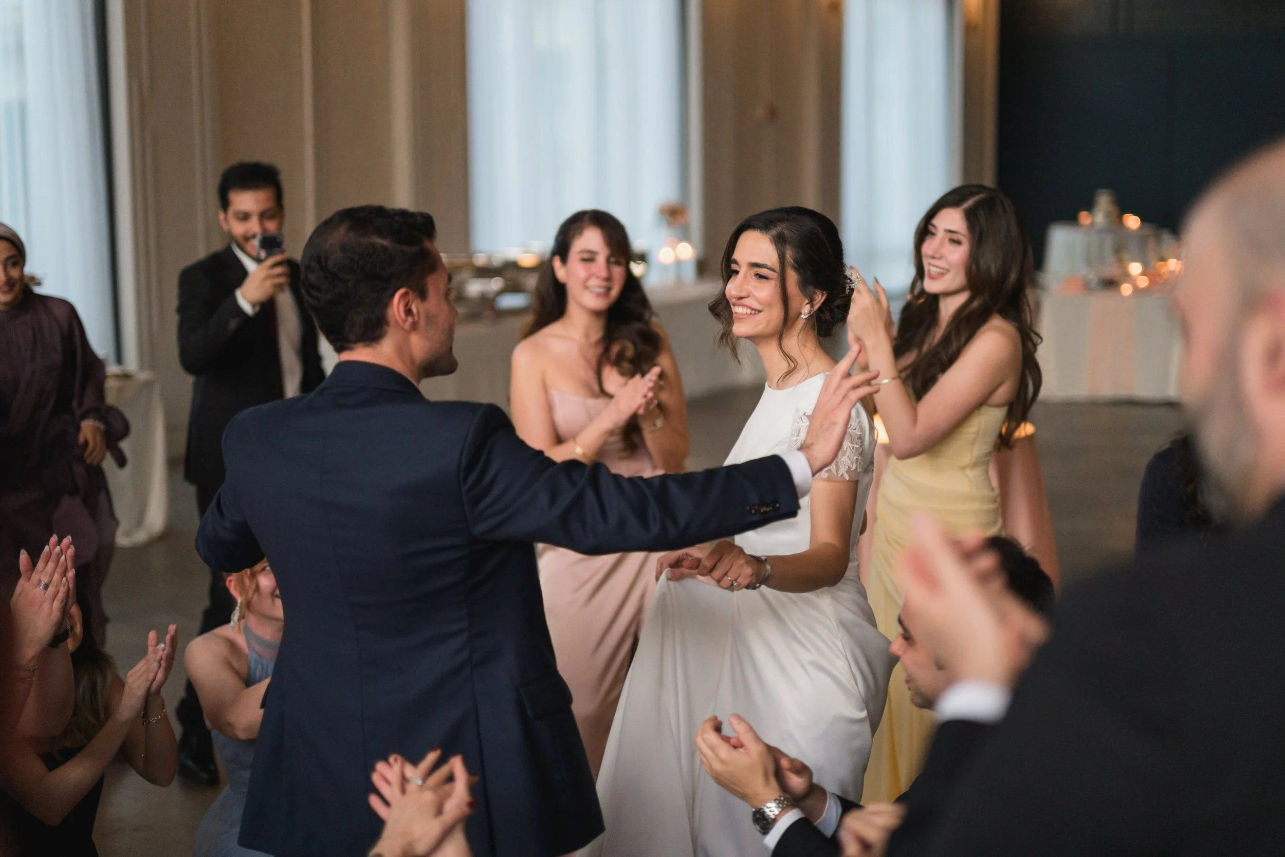 Bride and groom appear to be dancing and smiling during their wedding reception at PINE in NoDa, Charlotte. Guests clapping in the background