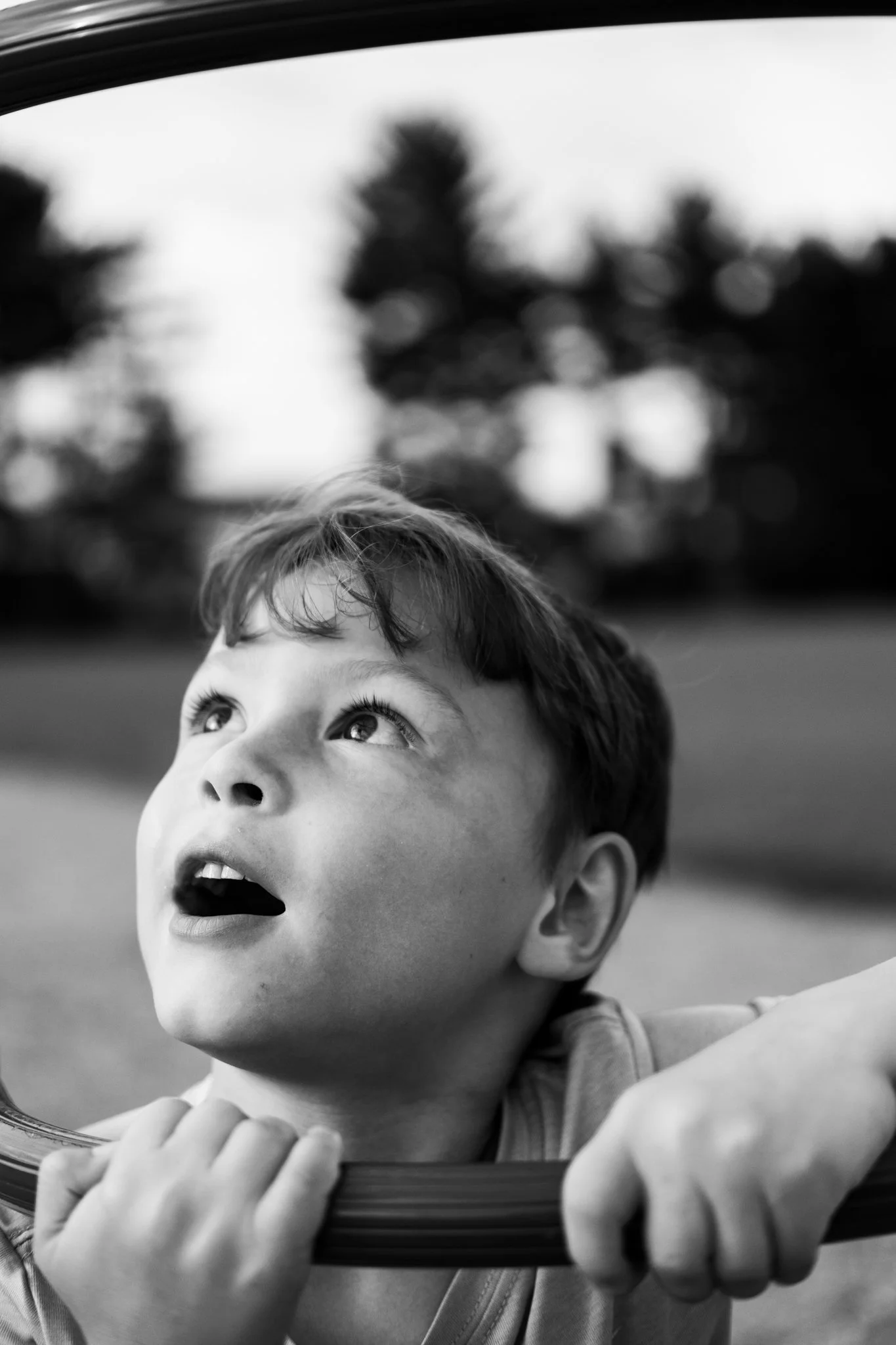 A young boy looking up through a mirror, with a blurred outdoor background.