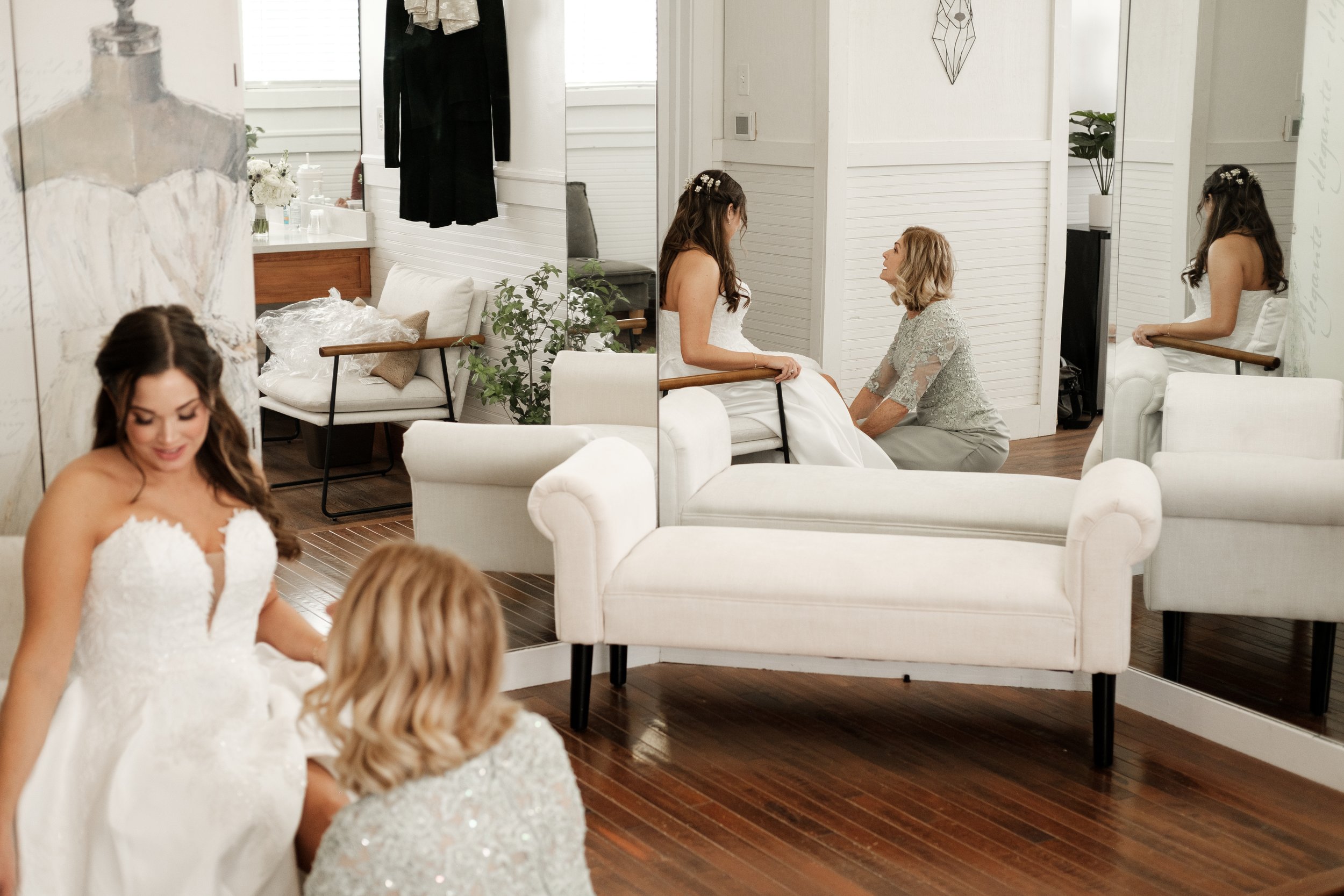 Brides mother putting on brides shoe before wedding in a dressing room that shows their reflection at Founders Dairy Barn