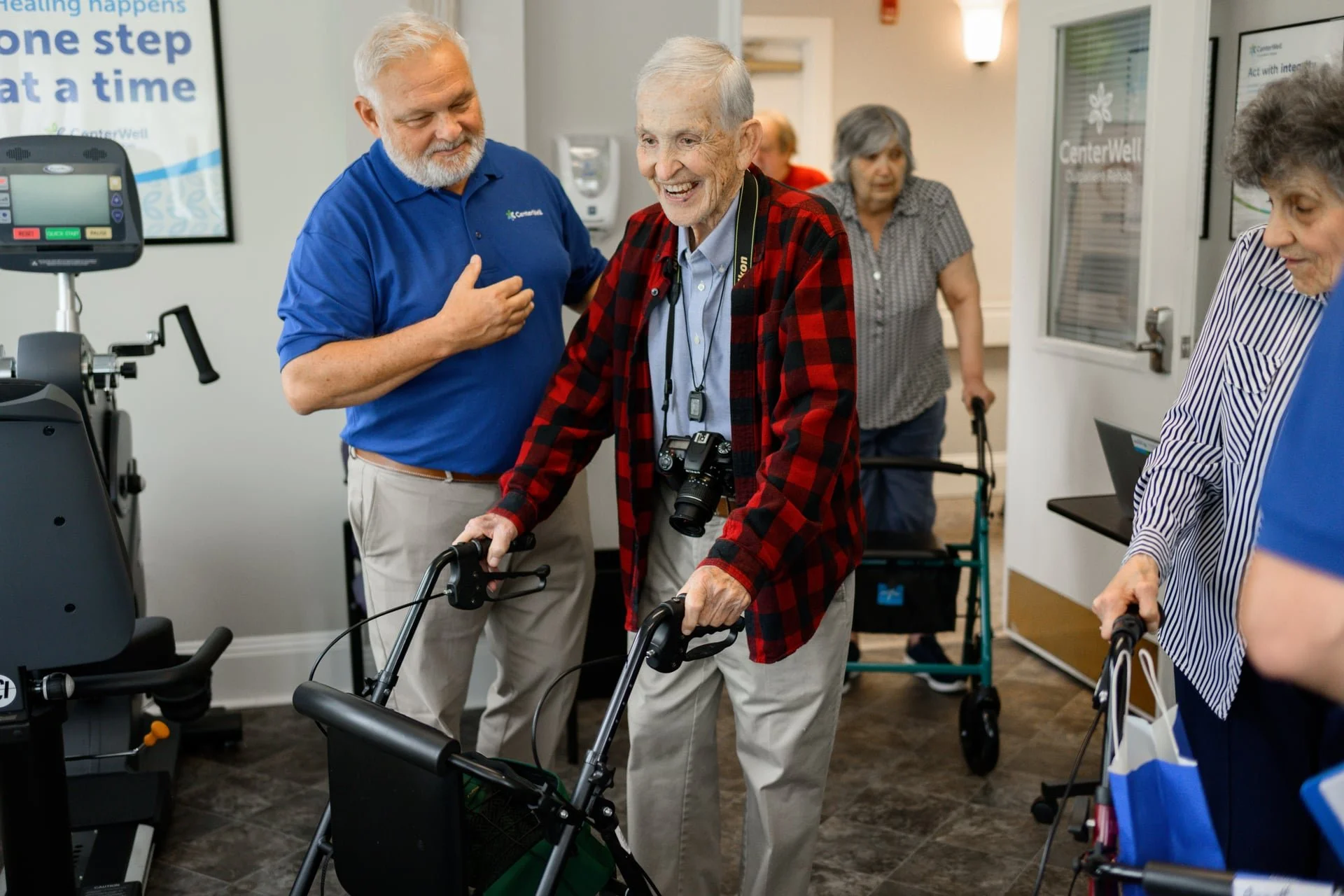Old man wearing a flannel and a camera around his neck during an event at a retirement home