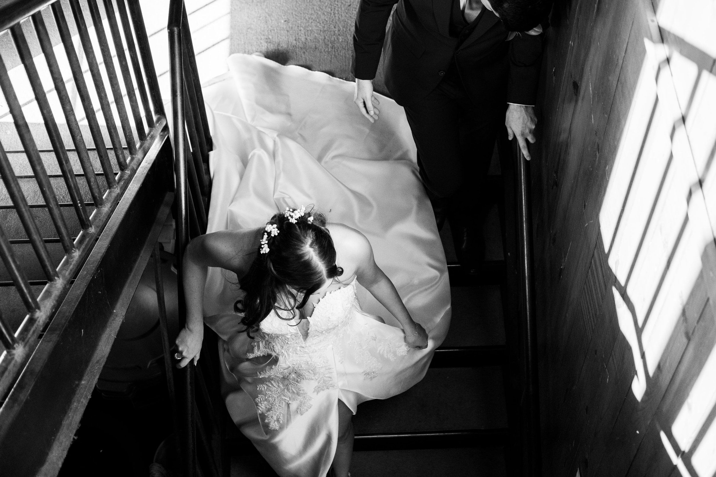 Bride in white dress walking down a stairwell during their wedding photography at Founders Dairy Barn.
