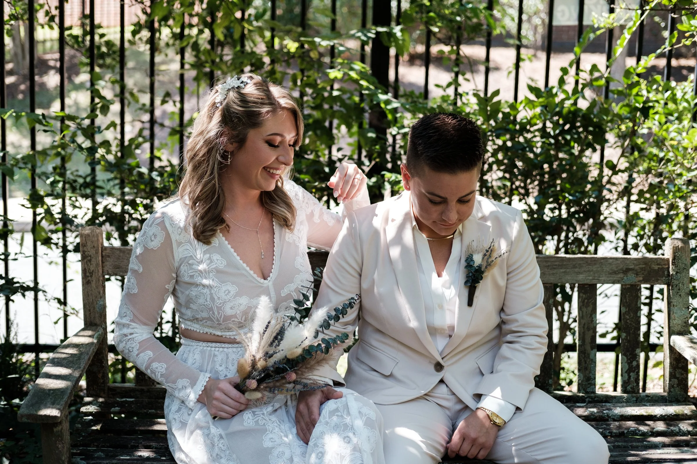 gay couple just married laughing and sitting on a bench at McGill Rose Garden by Brandon Pickett Photography