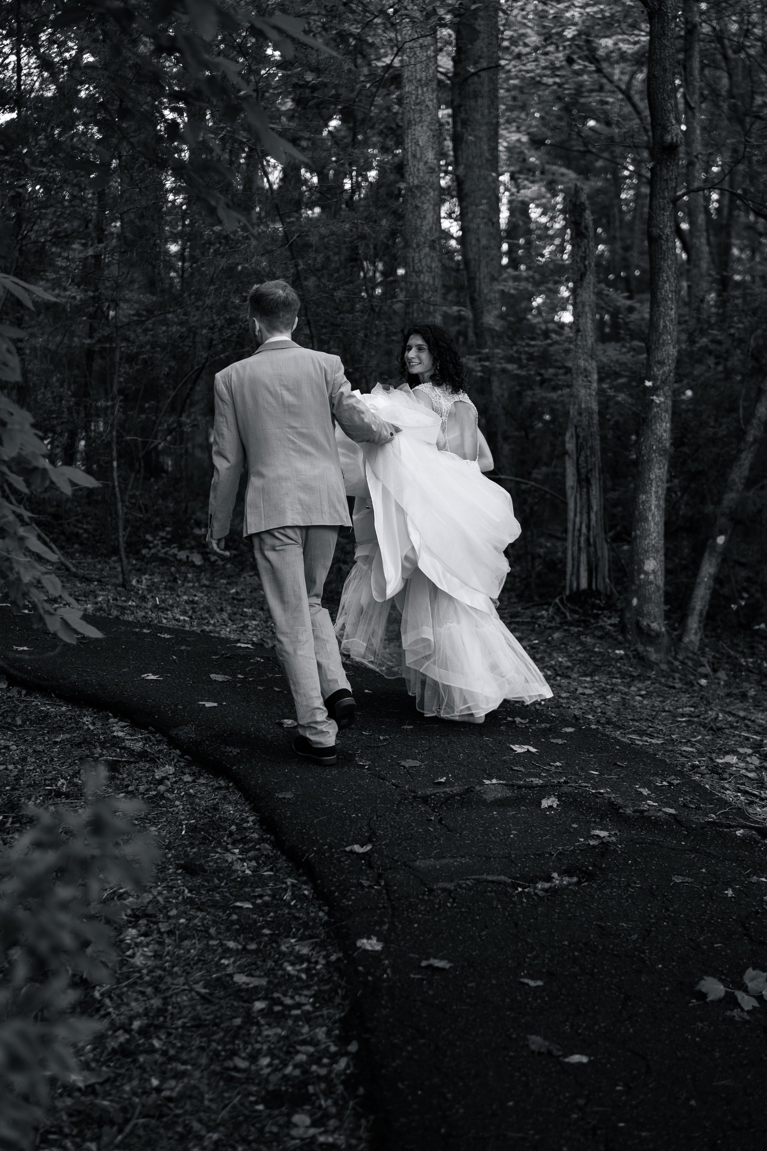 Groom holding brides dress uyp as she turns and looks back at a wedding ceremony on Lake Norman