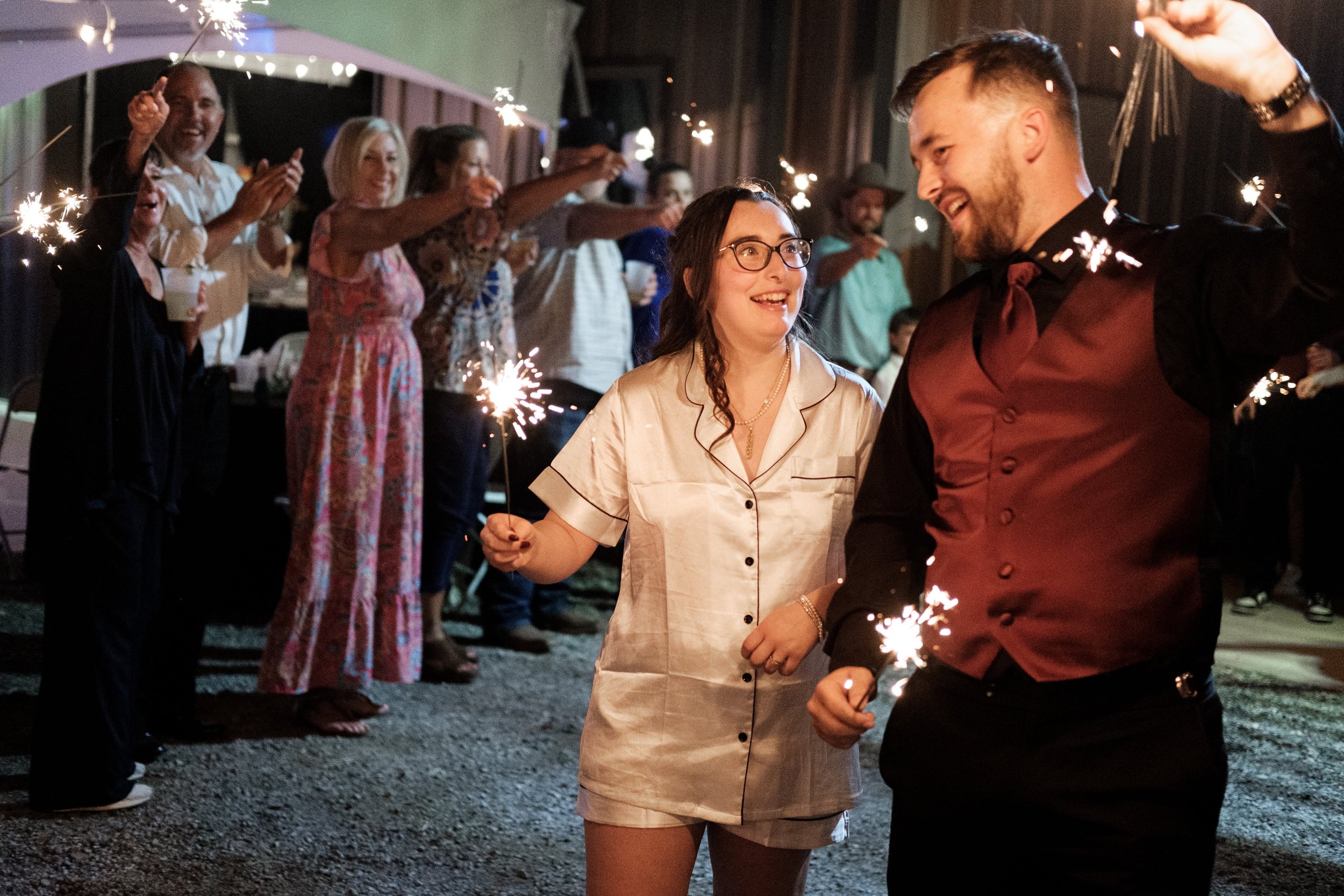 People celebrating with sparklers at night, smiling and enjoying the event.