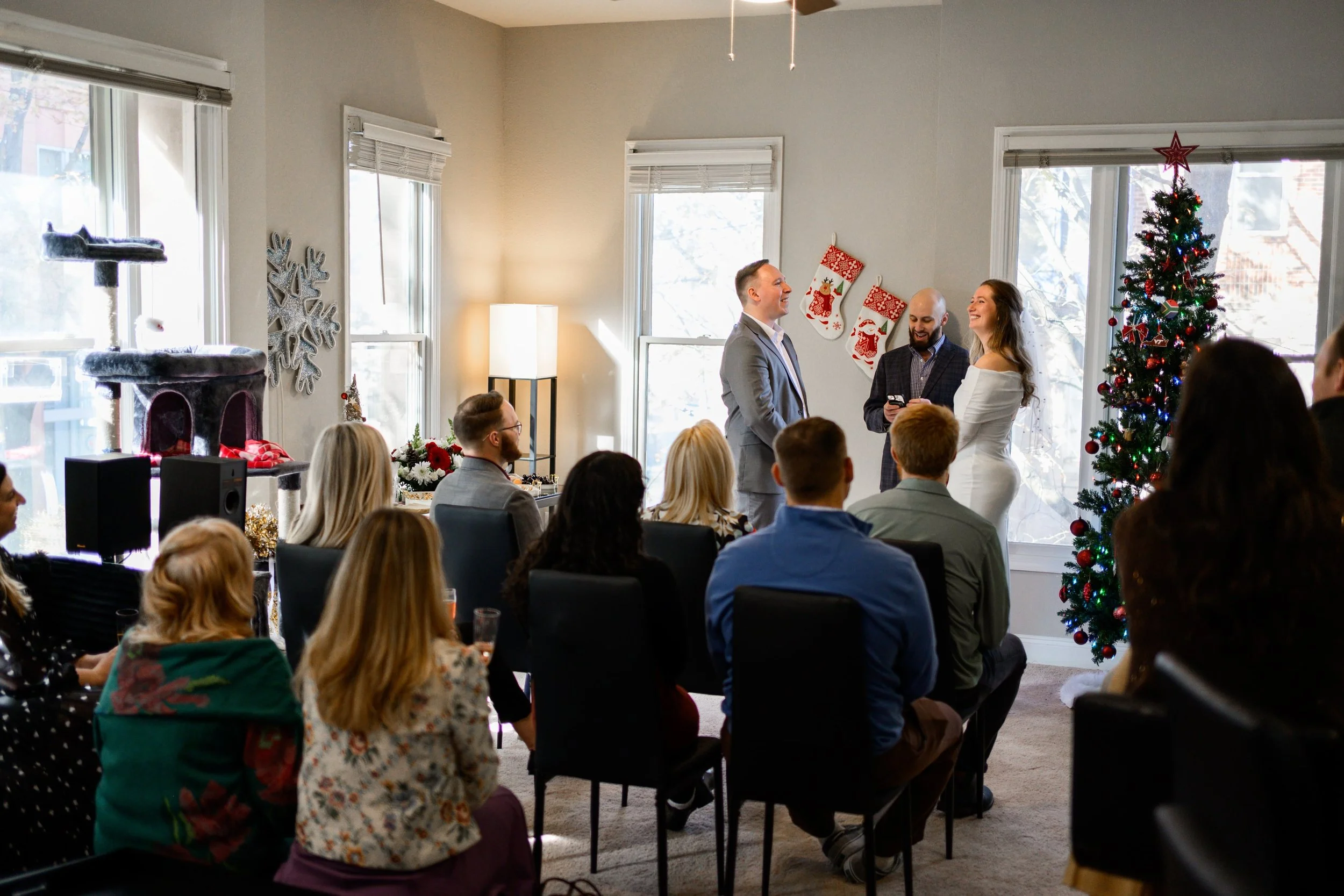 Bride and Groom smiling at each other during a small, intimate wedding in their apartment, surrounded by family and friends.