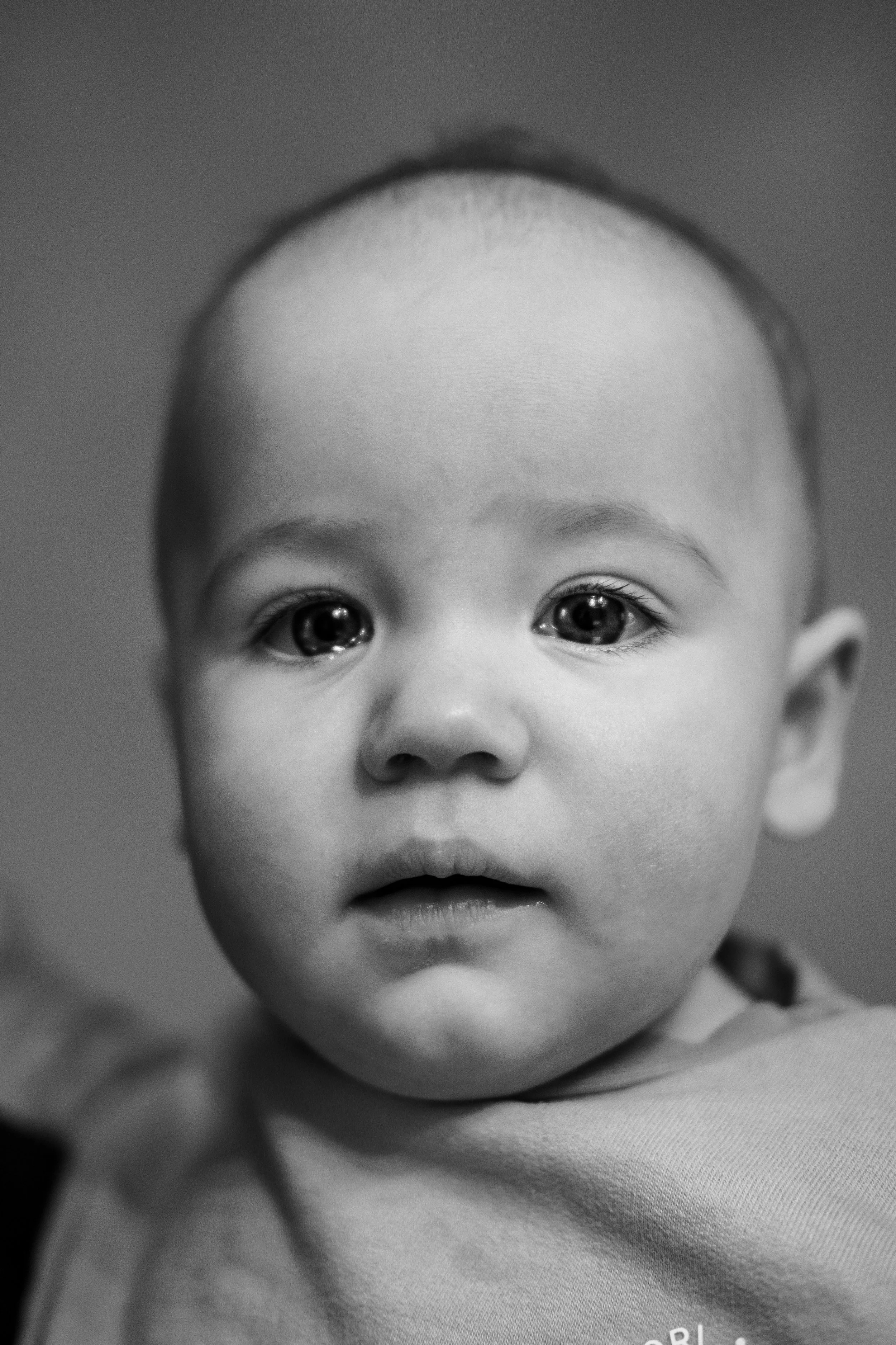 black and white emotional photo of a baby girl looking at the camera with tears in her eyes