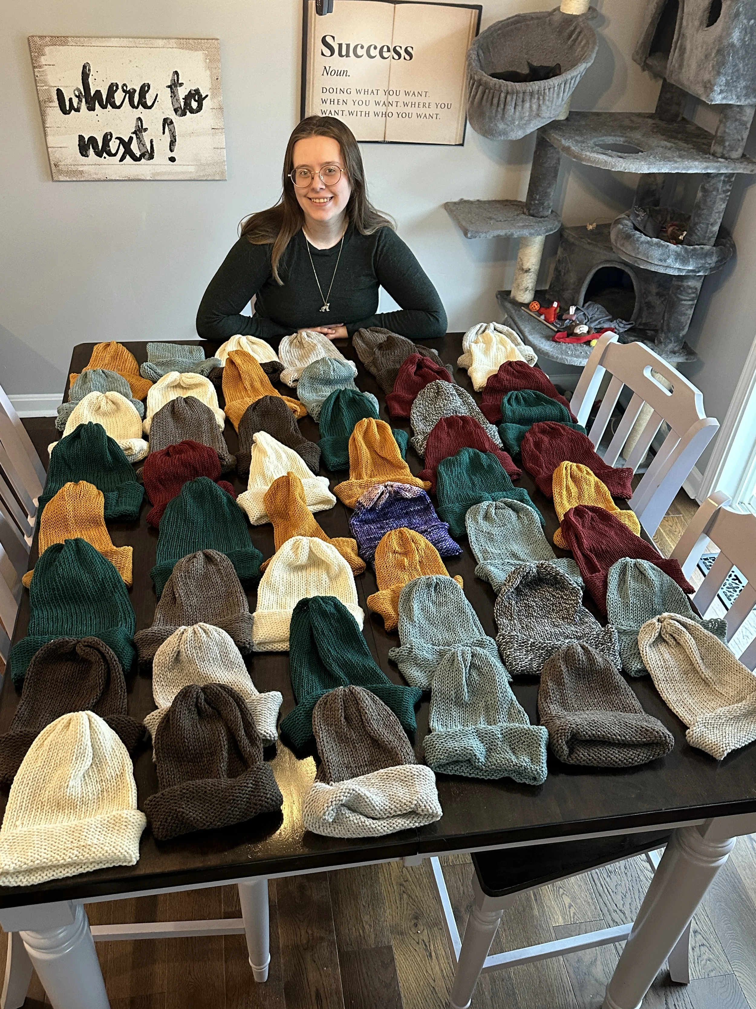 Stacy with her 50 knit hats before donating in 2024