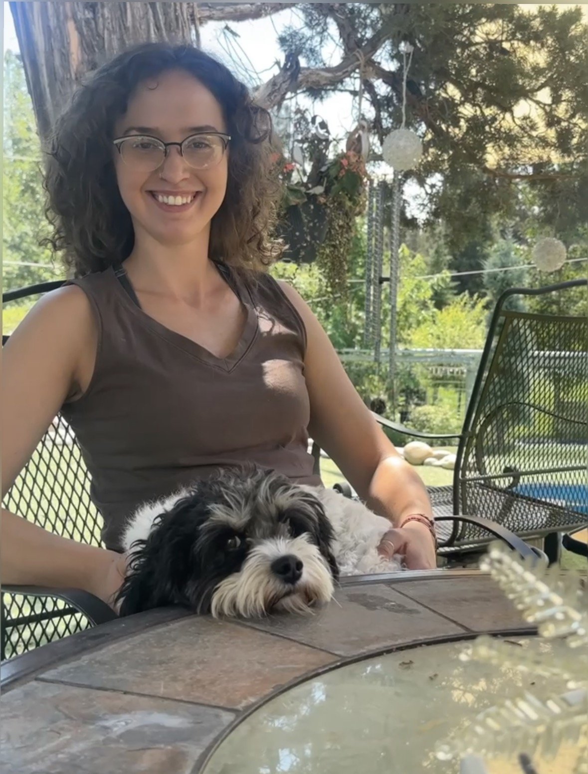 Maryna sitting outdoors with a small dog in her lap.