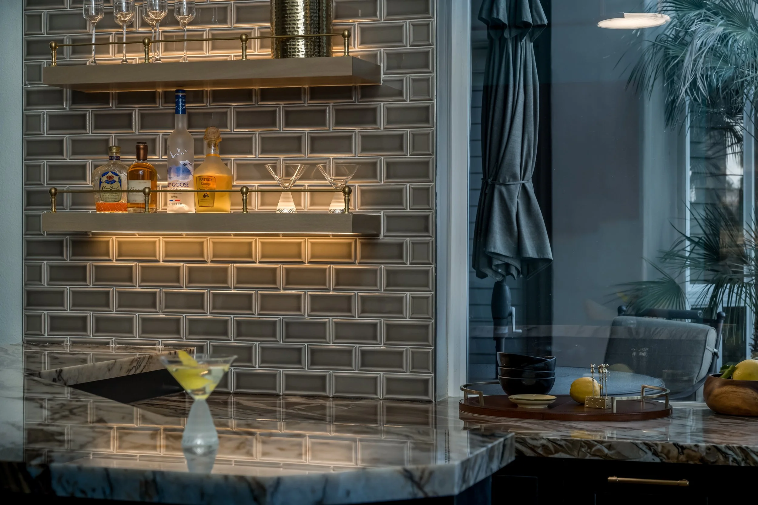 Custom Rancho Pointe home bar with natural stone counter, brass details, dark cabinetry, and open shelving