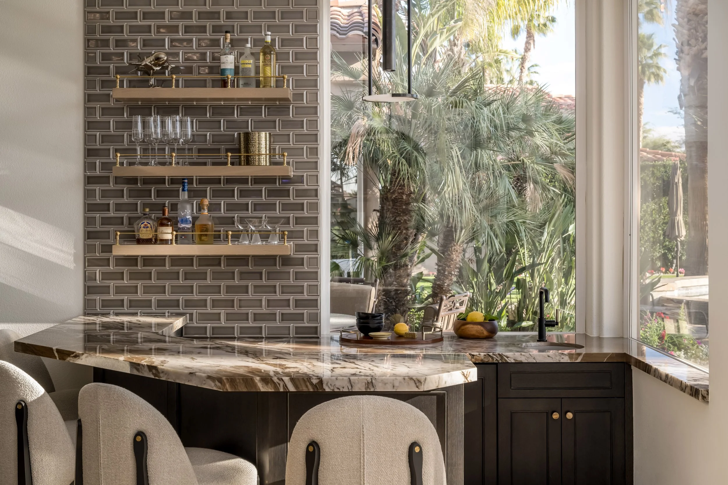 Rancho Pointe home bar in La Quinta with stone counter, upholstered seating, open shelves, and palm views