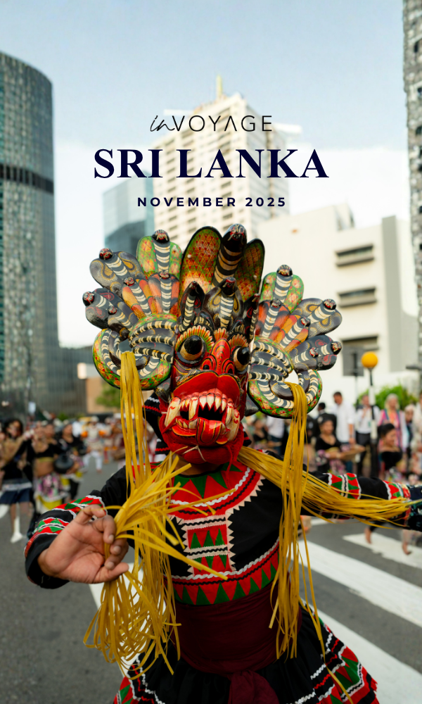 Festive parade in Sri Lanka featuring traditional dancers and musicians, with spectators taking photos and watching in an urban setting.