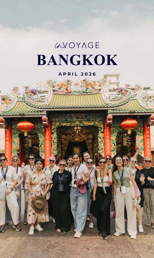 A group of people in traditional Thai costumes and casual attire celebrating at an event in Bangkok, April 2026, with some holding drinks, and a few wearing traditional masks and accessories, posing for a group photo in a decorated indoor setting.