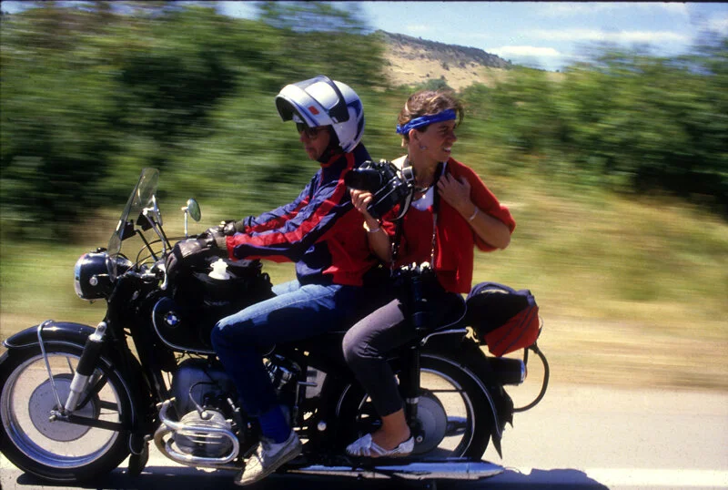 Julia Dean gets a lift from a motorcycle while covering the Coors Classic bicycle race in 1985.