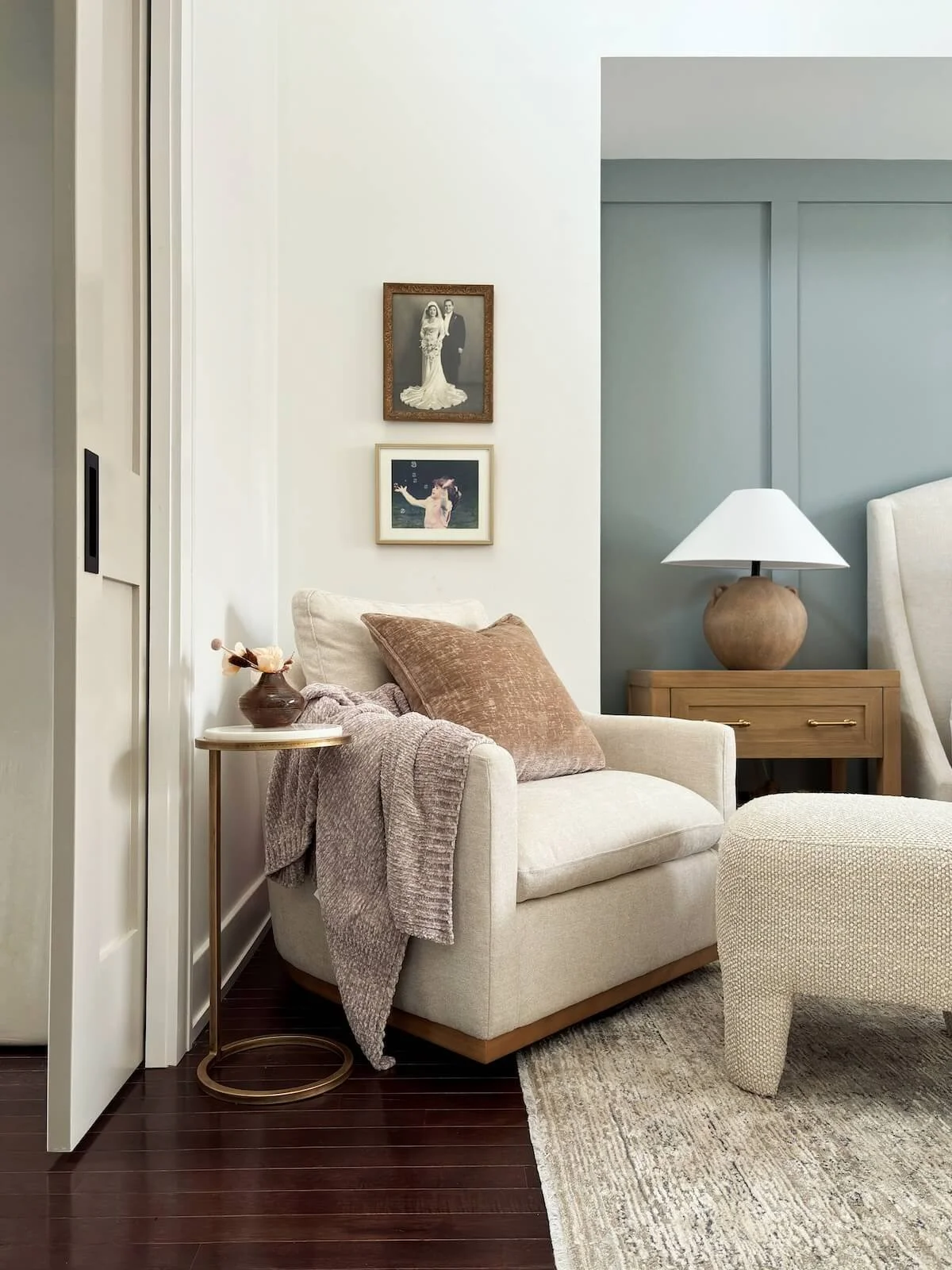 Cozy interior with a cream colored sofa chair draped in a velvet blanket and pillow.