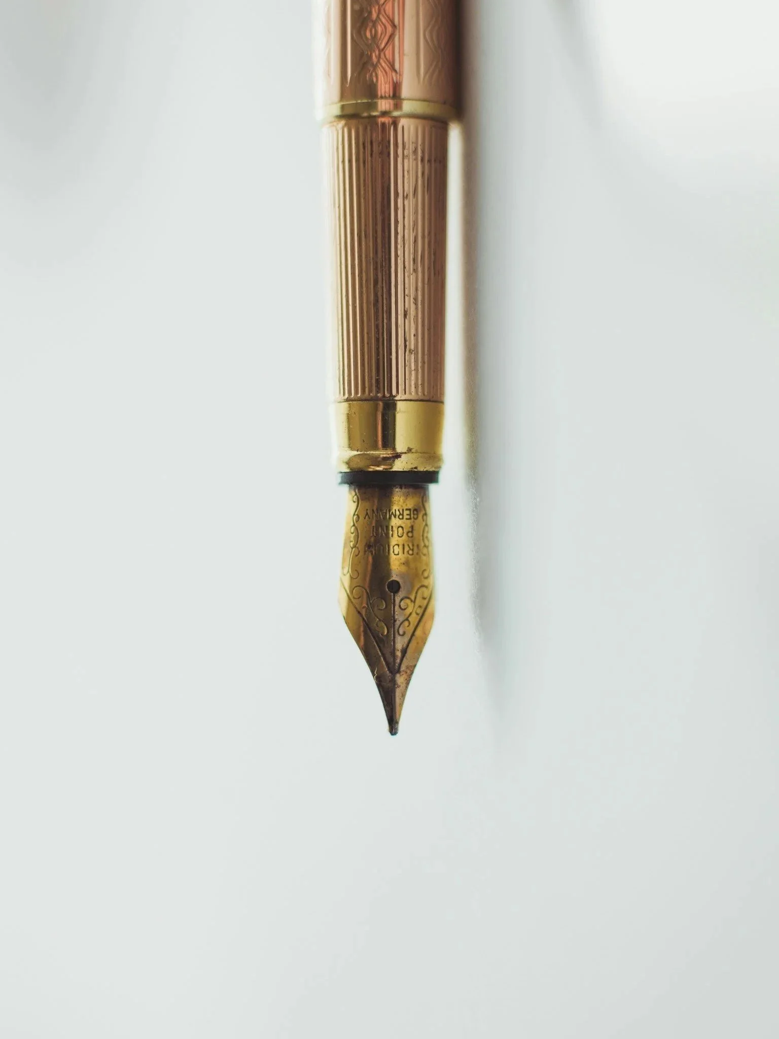 Close-up of a gold fountain pen nib on white paper.