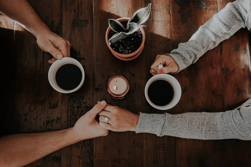 A couple holding hands drinking coffee