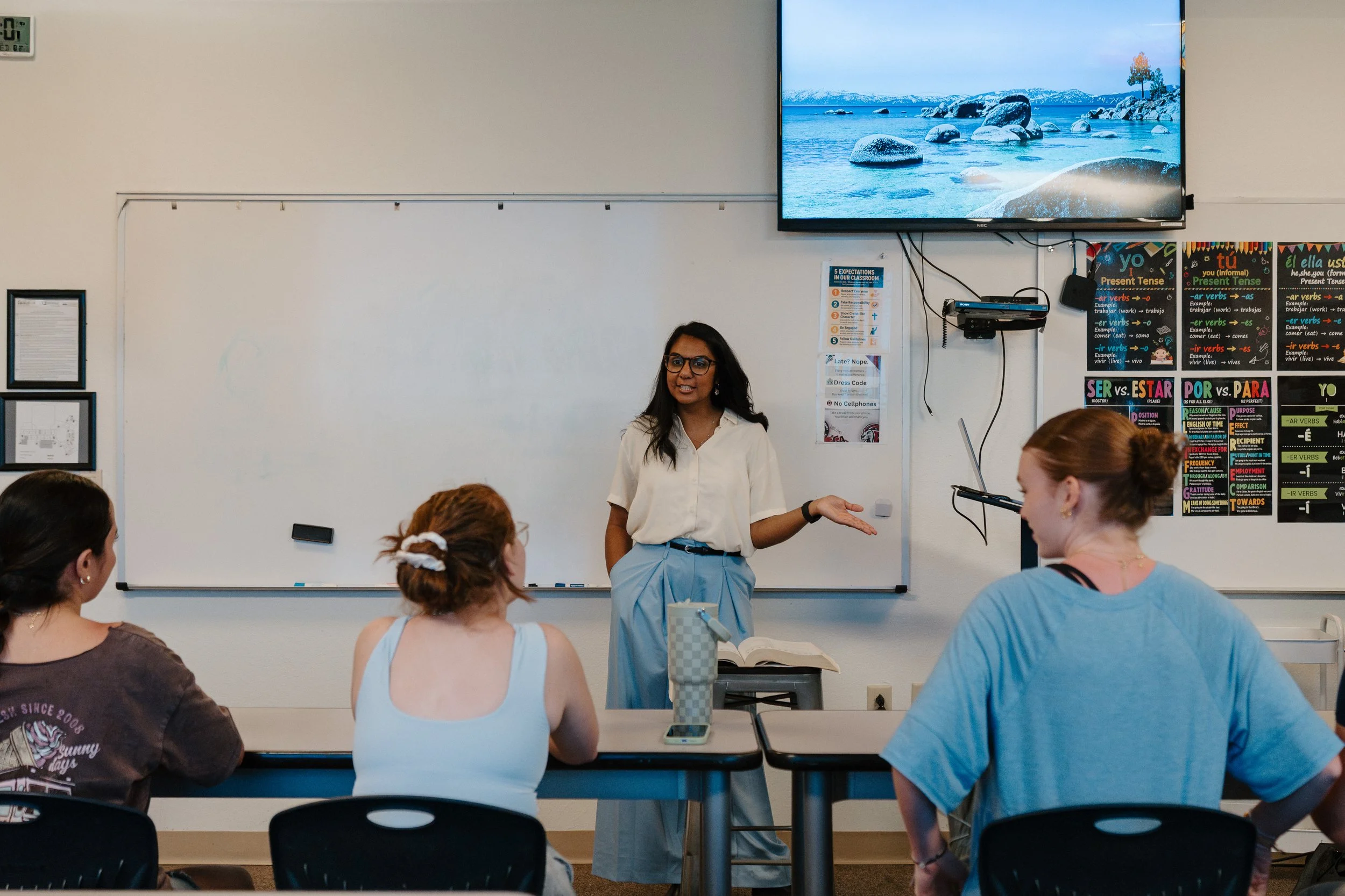 Photo of Ardiendo Director and Test Prep Coach, Sierra, teaching at the front of a classroom in front of a white board with three students sitting in a row in front of her at desks.