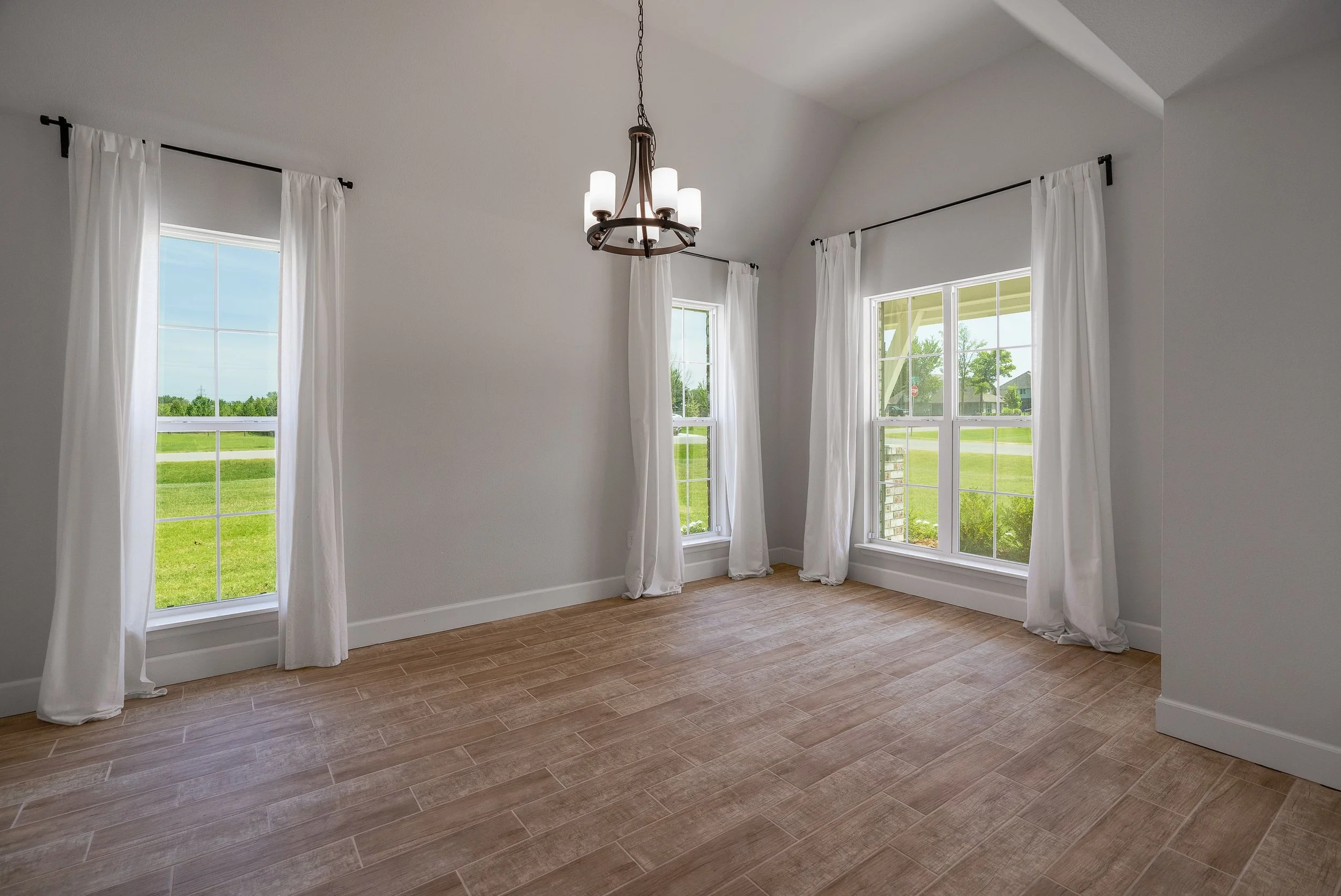 Large dining room with white walls and 3 windows showing a clear view outside