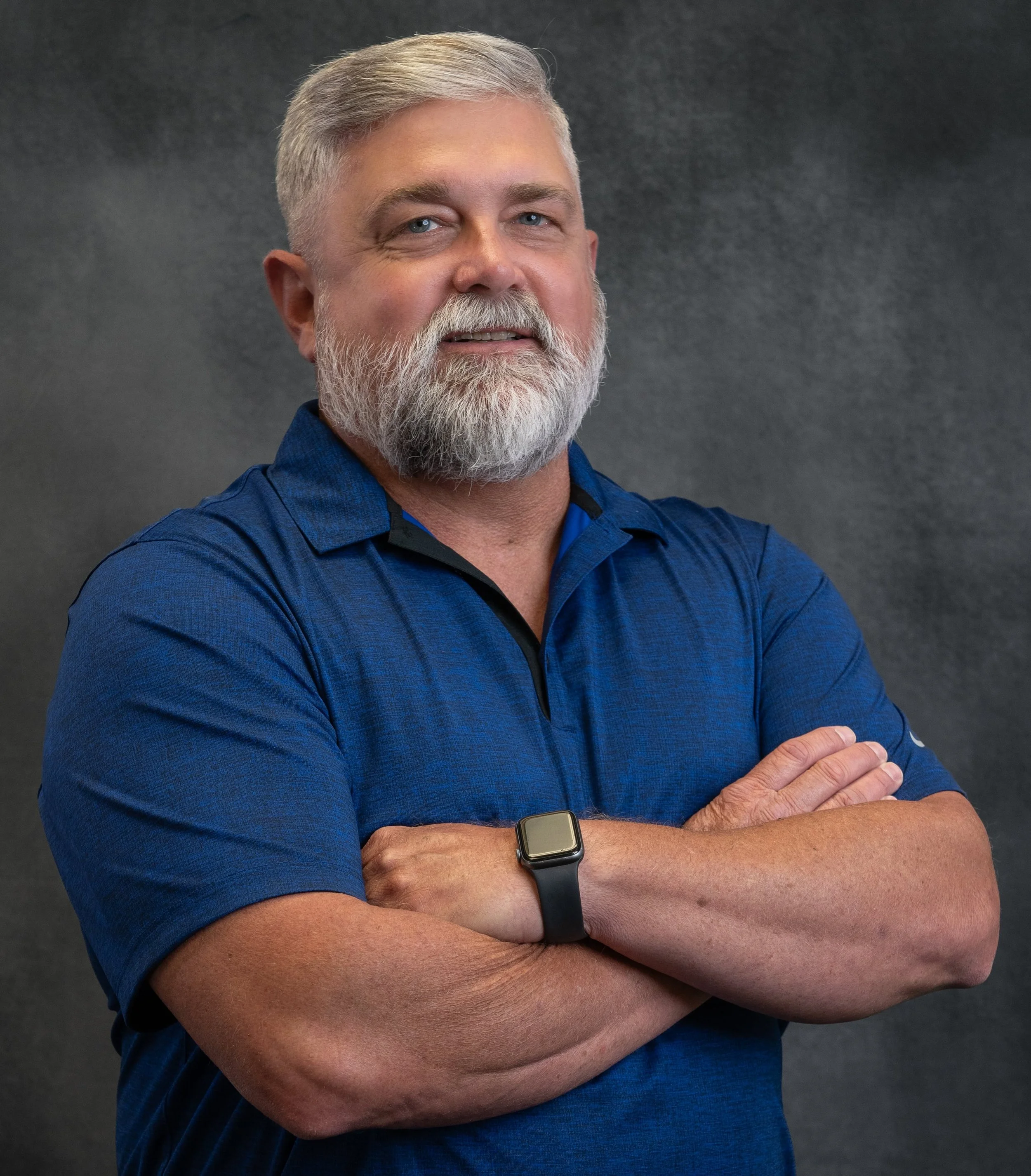 Photo of a stocky white-haired man smiling and wearing a blue shirt