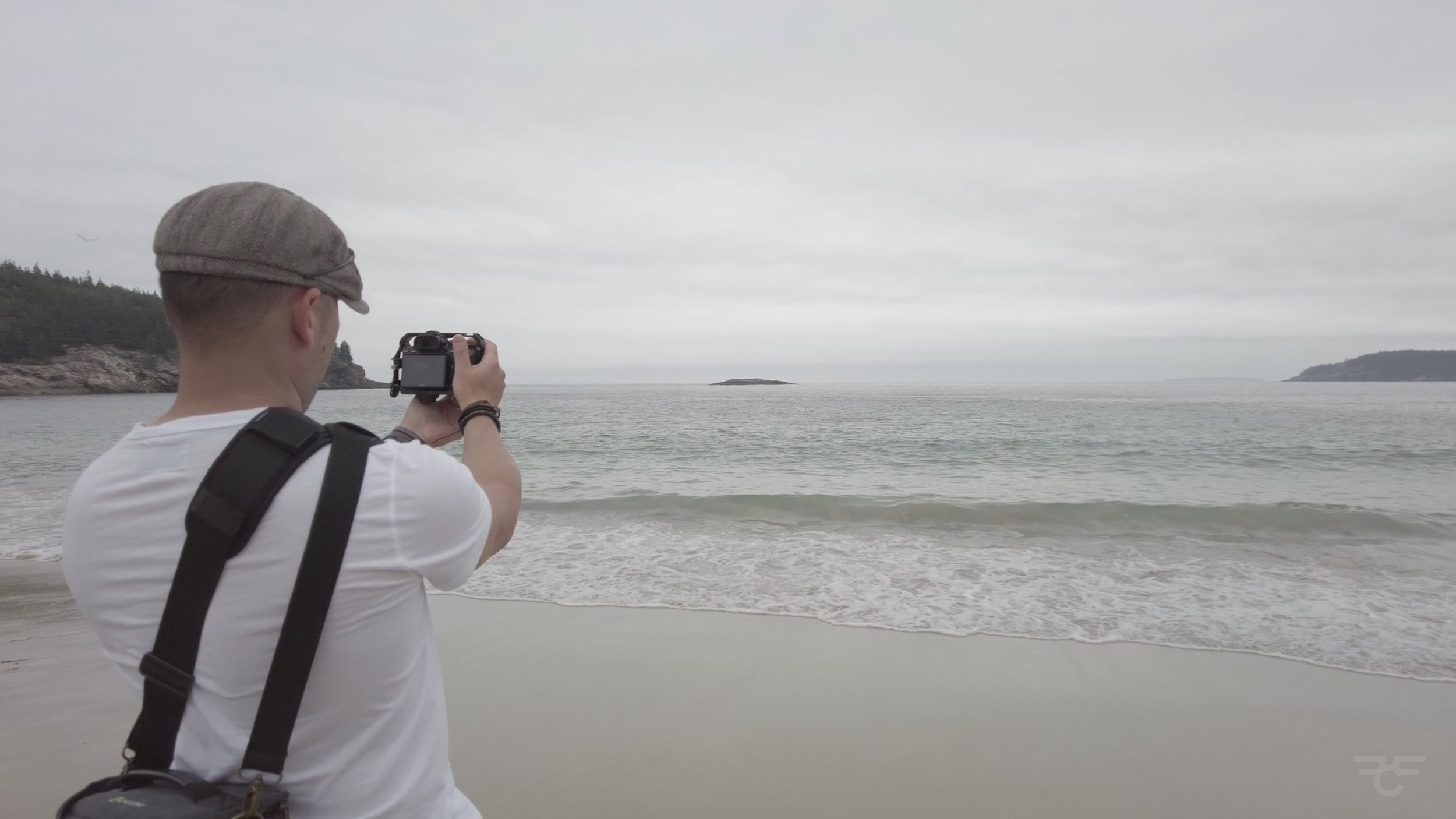 A photo of me at Sand Beach as I capture a photo with my camera of the Atlantic Ocean