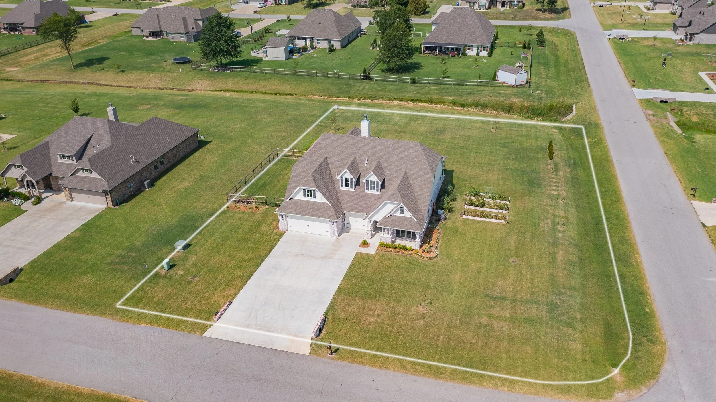 Drone photo of a large white 2-story home on a corner lot