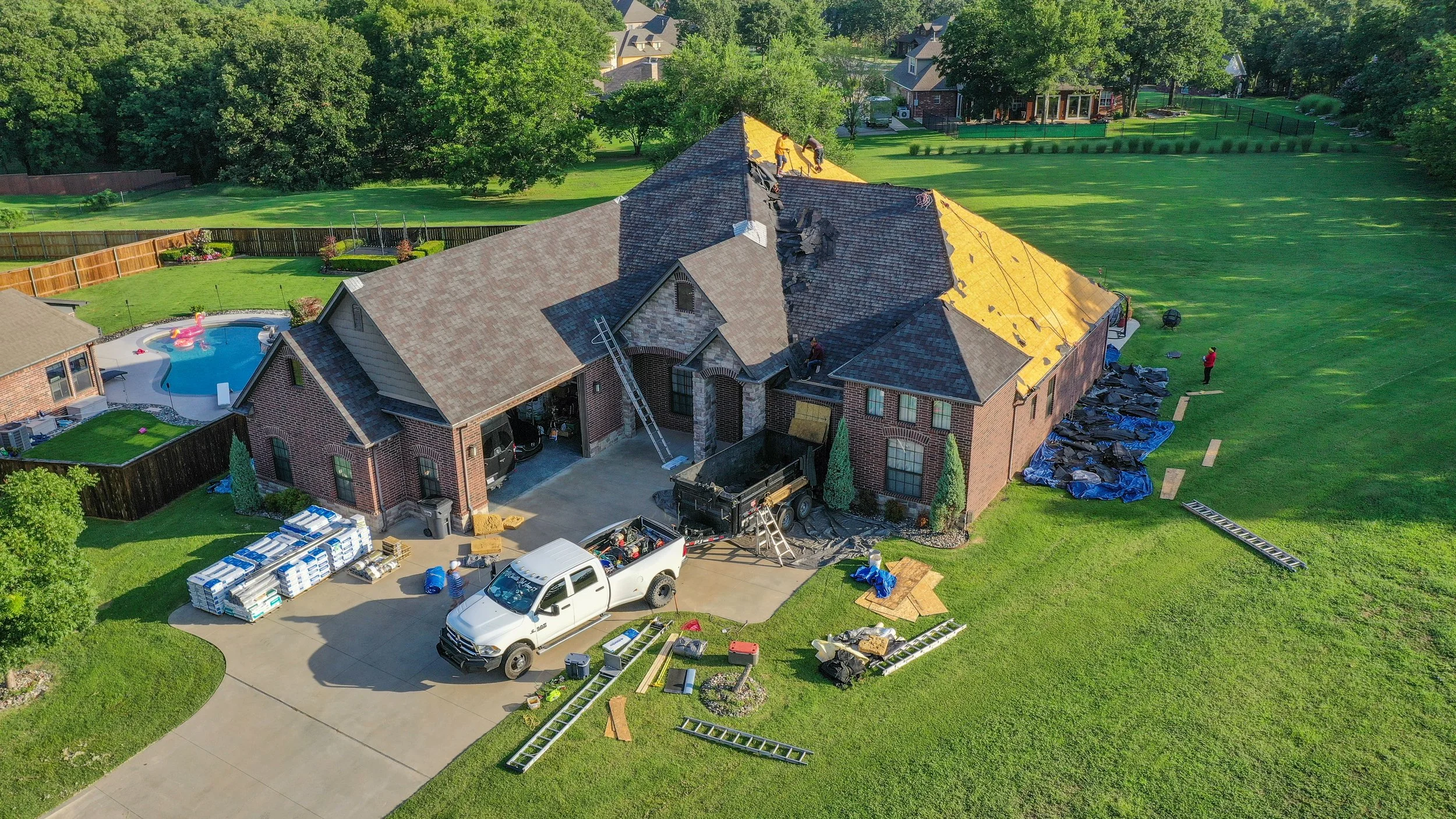 Drone photo of a large brick house getting a roof replacement