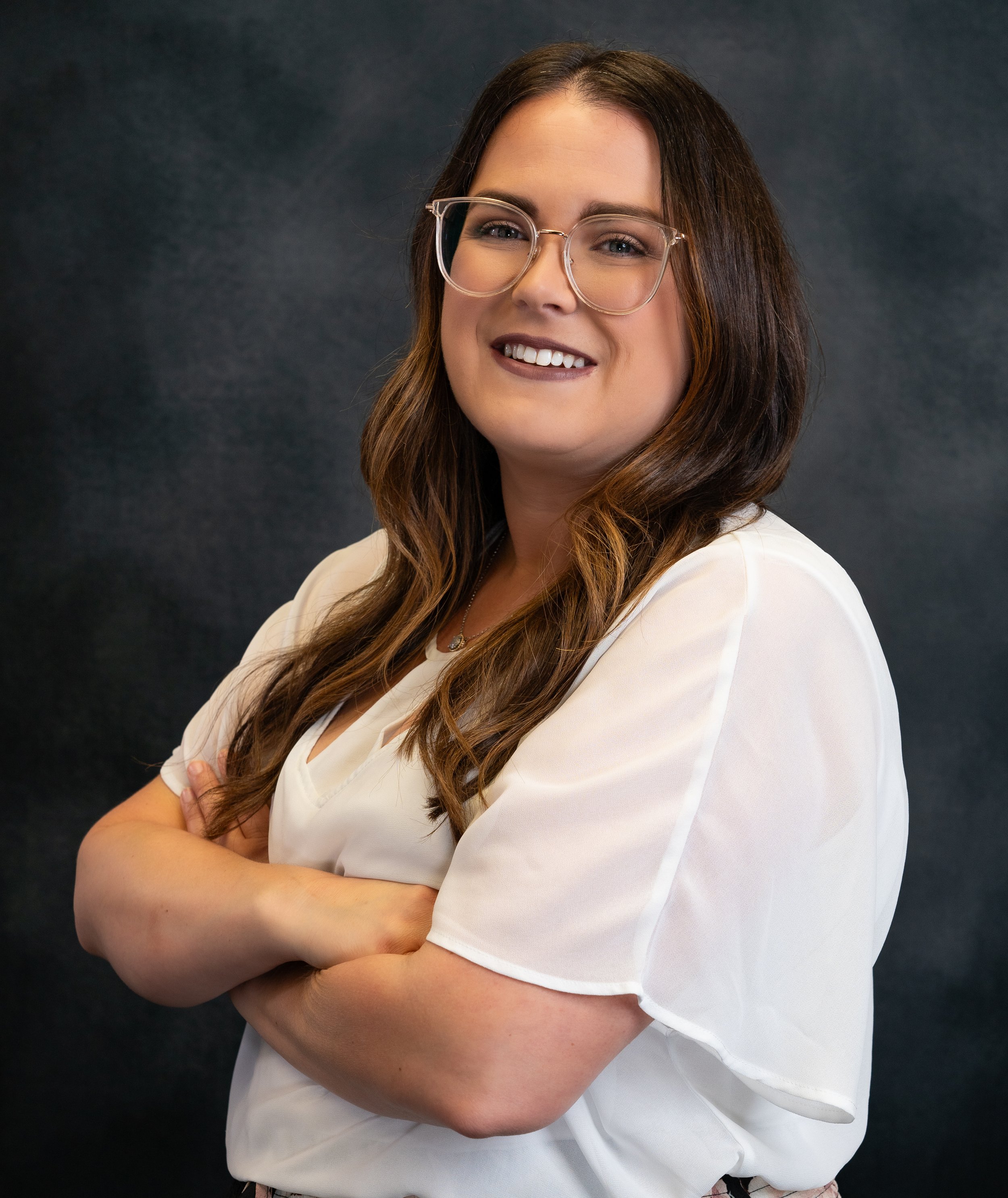 Photo of a brown-haired woman who is wearing glasses and smiling