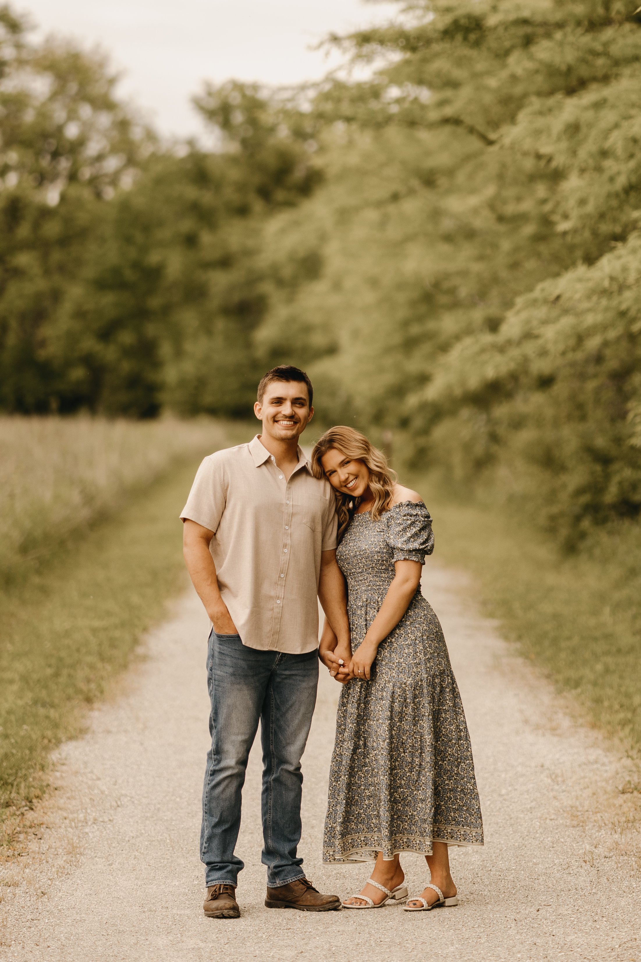 engagement session photography a couple smiles at the camera on a nature path during their photography session in Anderson Indiana