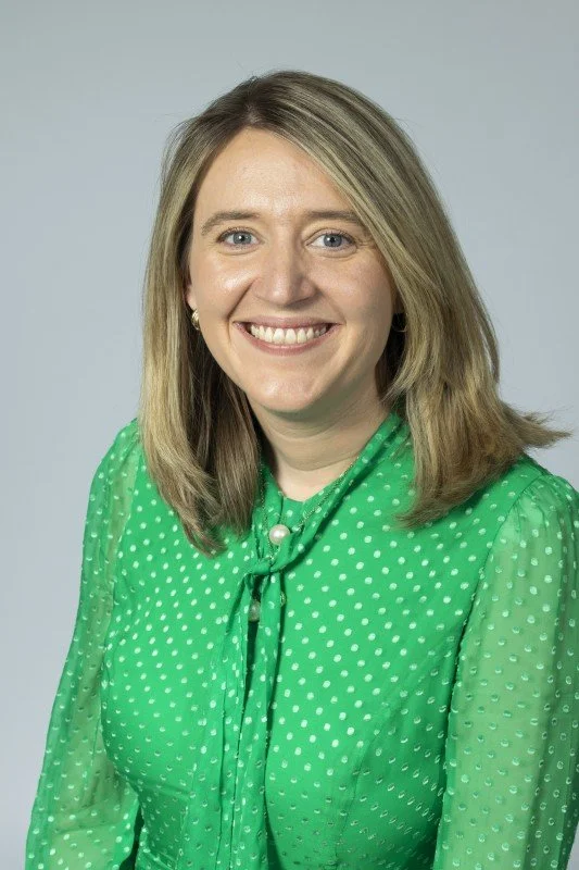 Headshot of Georgia Gould smiling directly at the camera wearing a green blouse on a grey backdrop.