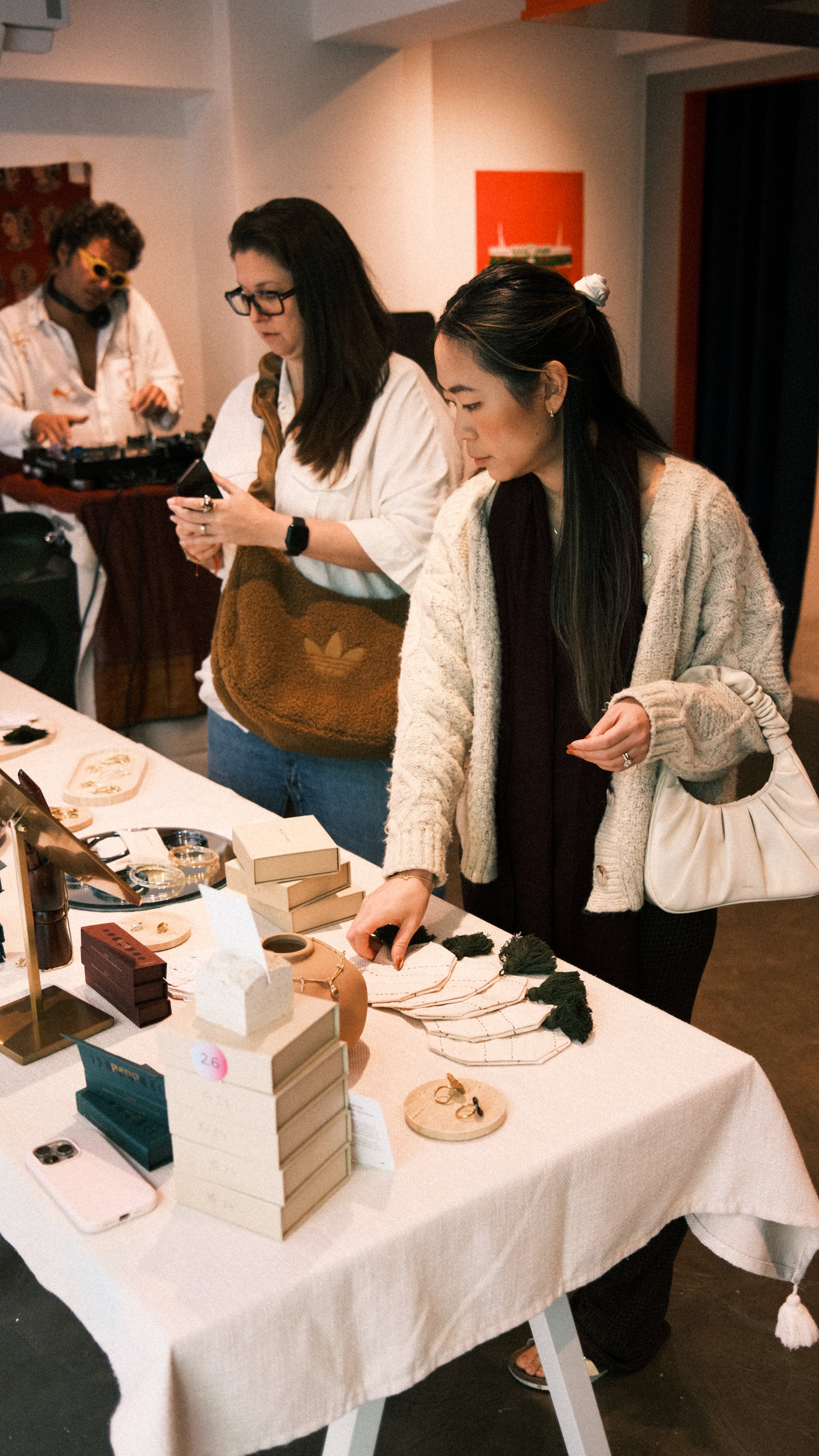 People shopping for jewelry at a market stall, with various jewelry items displayed on the table.