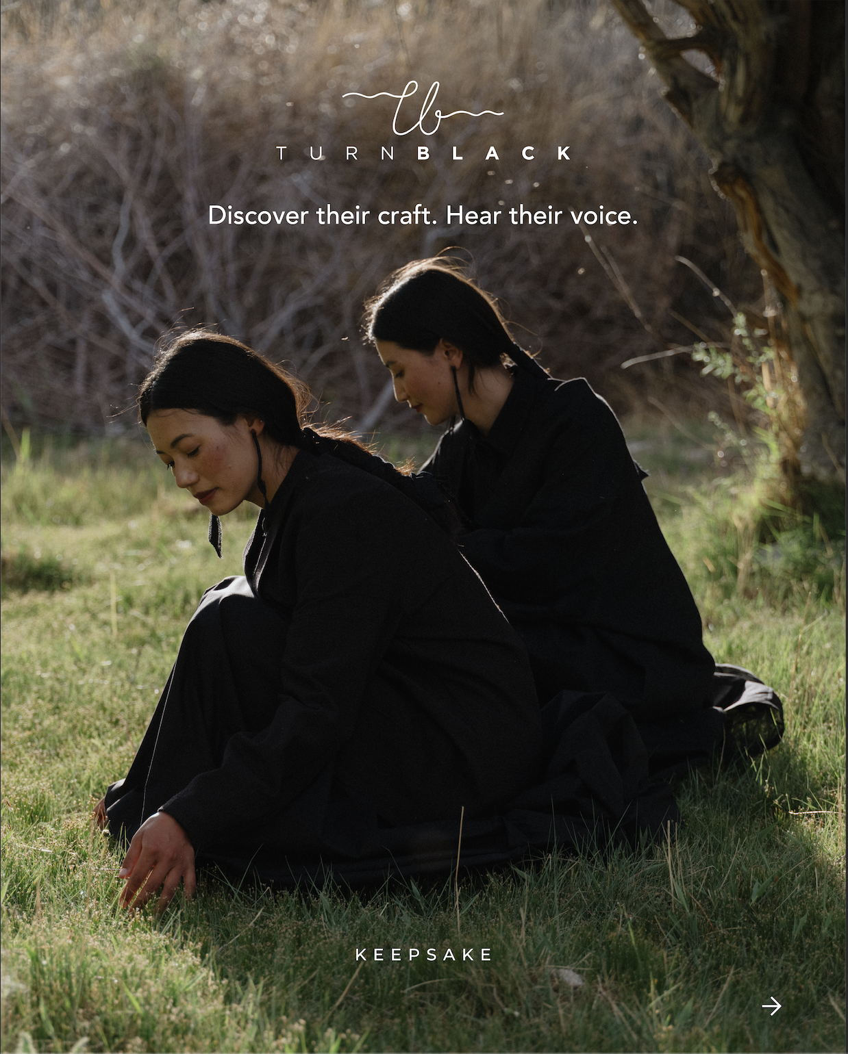 Two women dressed in black, sitting on grass in a natural outdoor setting, involving a tree and bare bushes in the background, with sunlight illuminating the scene. One woman is reaching out to the grass while the other looks down. Text on the image reads 'Discover their craft. Hear their voice.' and 'Keepsake' at the bottom.