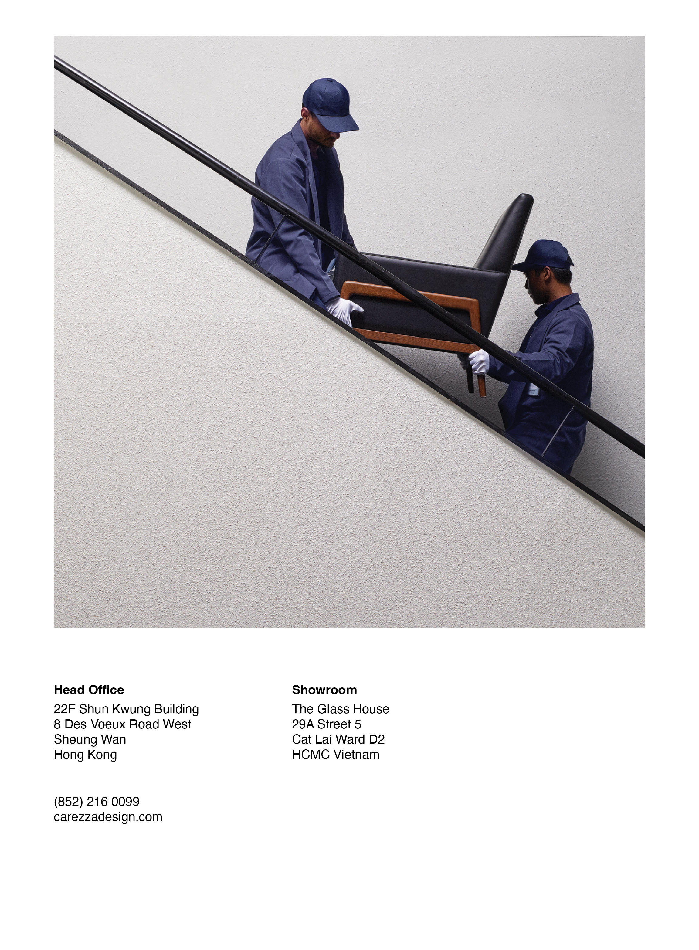 Two movers in blue uniforms lifting a chair up a staircase.