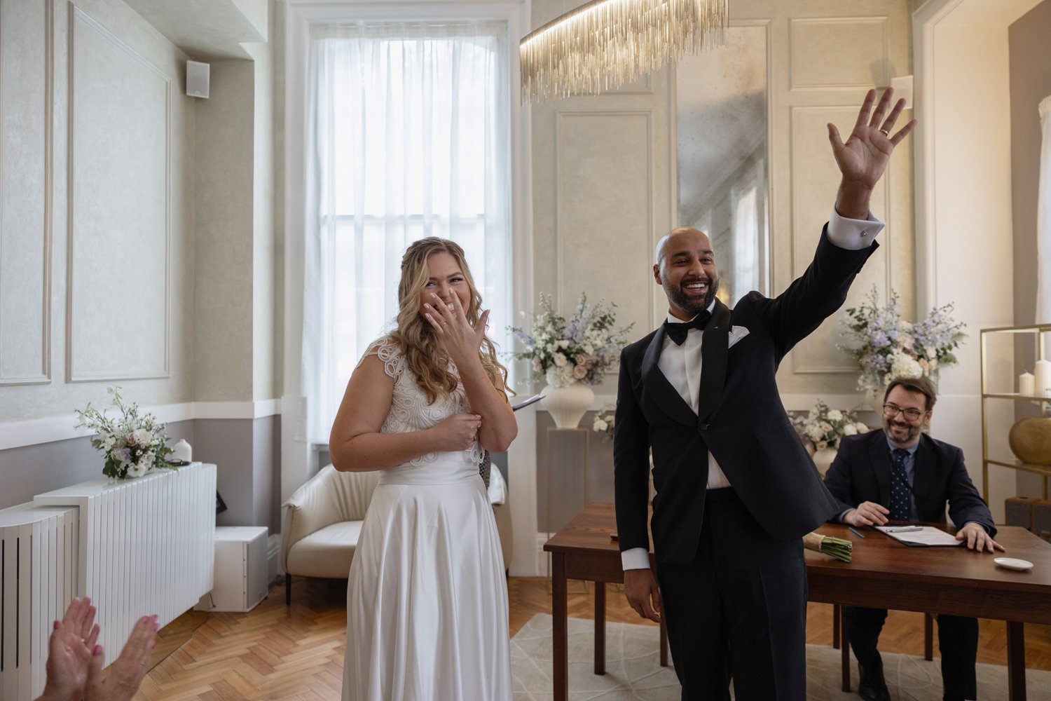 Just married and the bride and groom turn to their guests and show off their rings