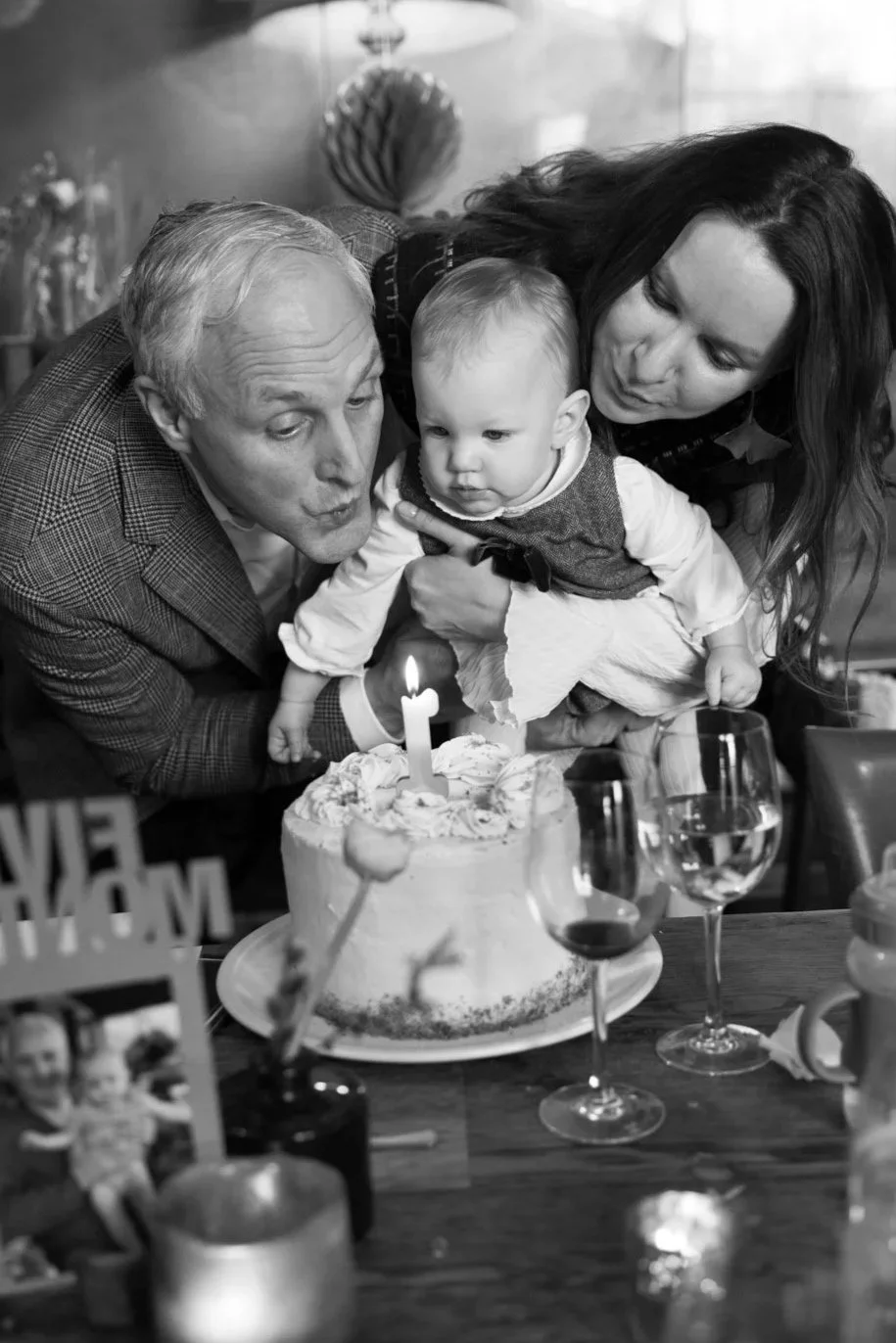 Parents help their baby daughter blow out her first birthday candle.