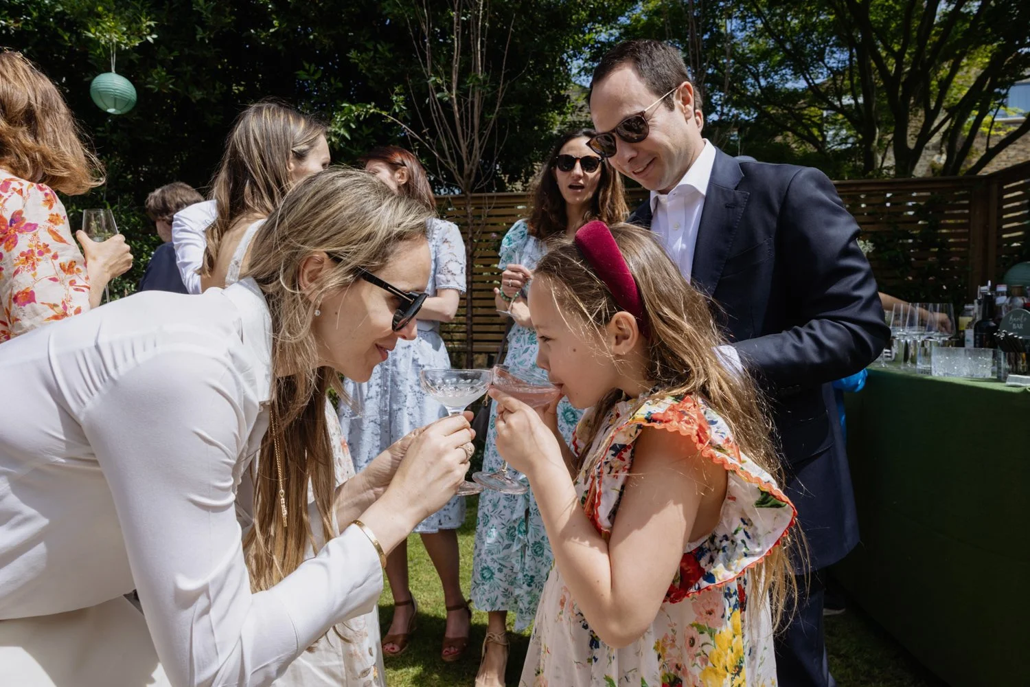 Young girl having her first sip of champagne with her mother.