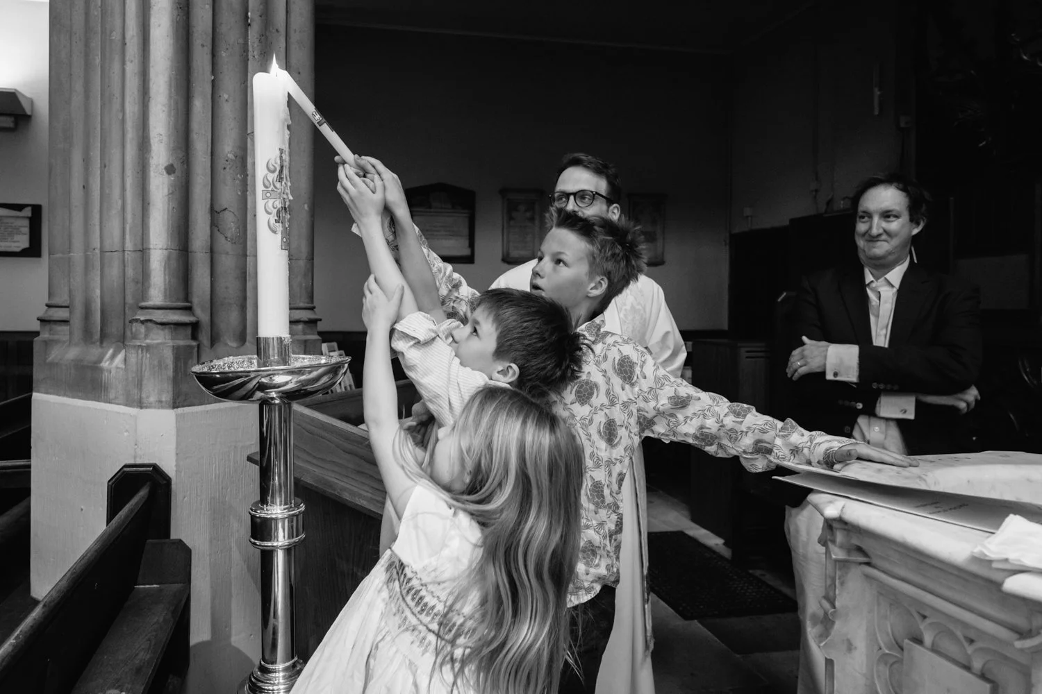 Three older siblings share the task of lighting the candle for their brother