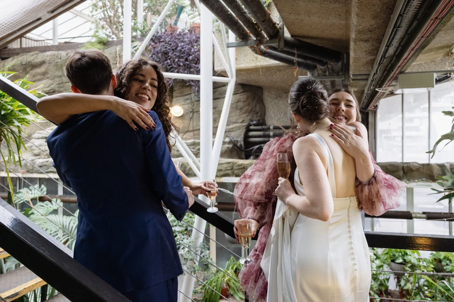 Bride and groom each hugging a guest each.