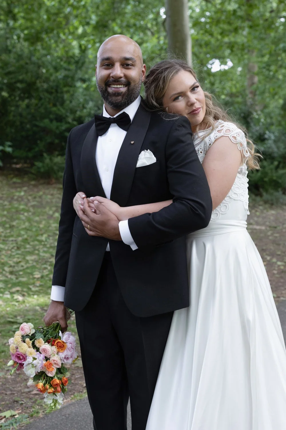 Bride hugging groom from behind and resting her face on his shoulder