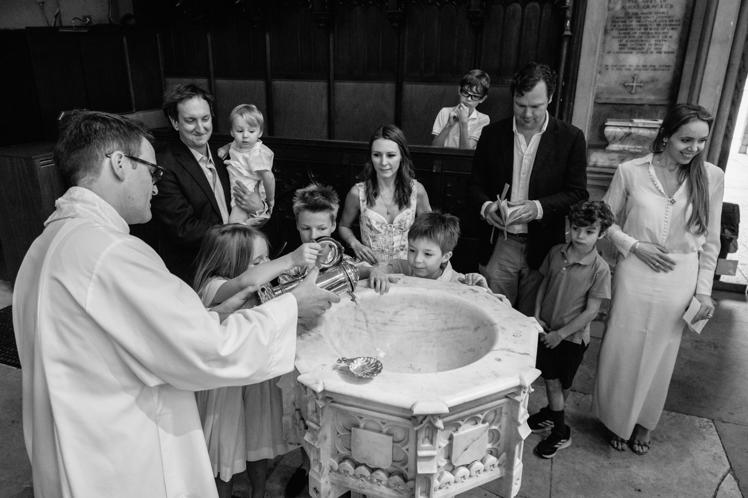 Siblings helping to pour the water into the font for their baby brother's christening