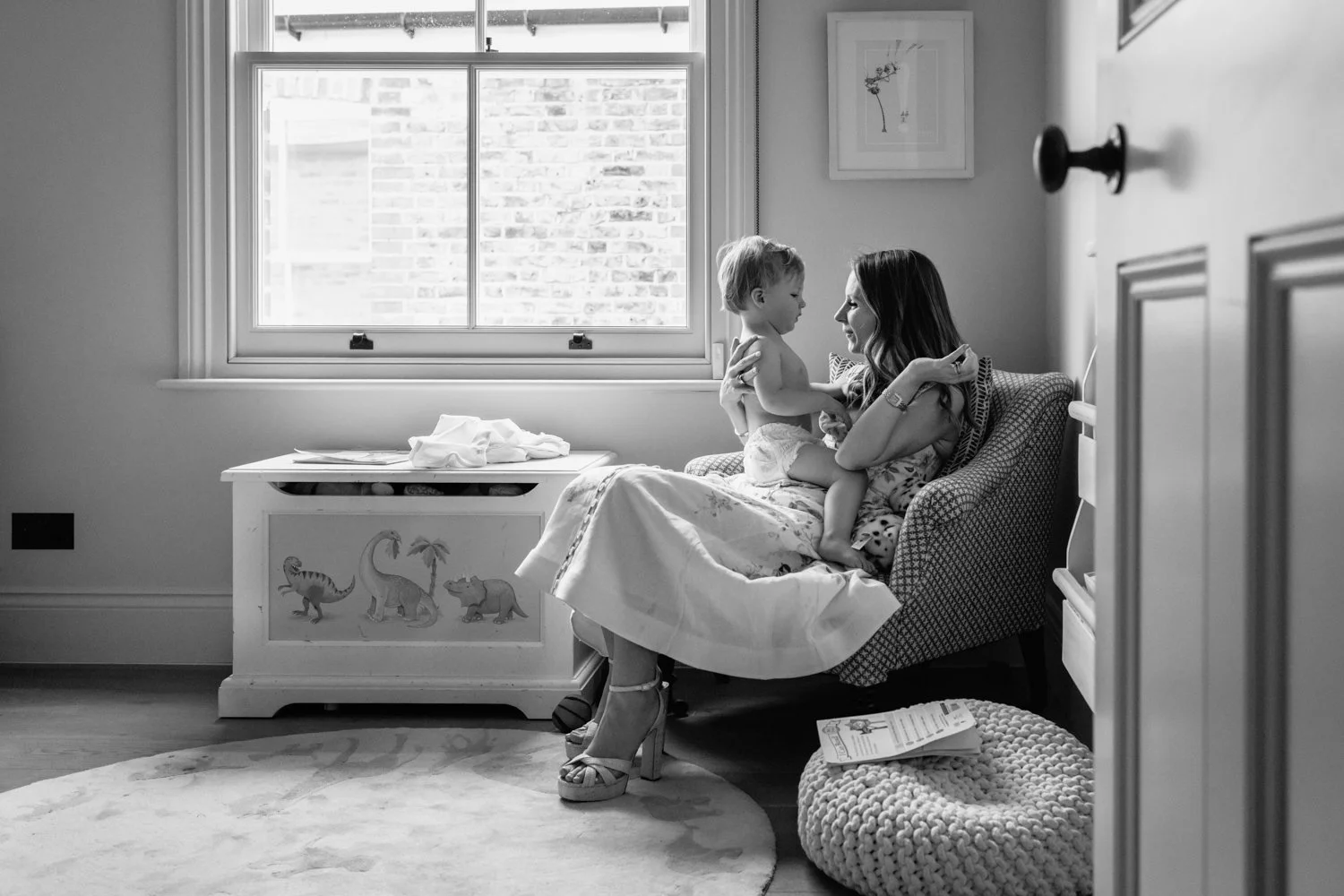baby boy seated on mother's lap in the nursery.