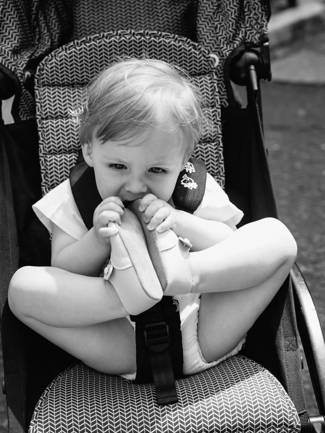 Baby chewing his shoes in pram