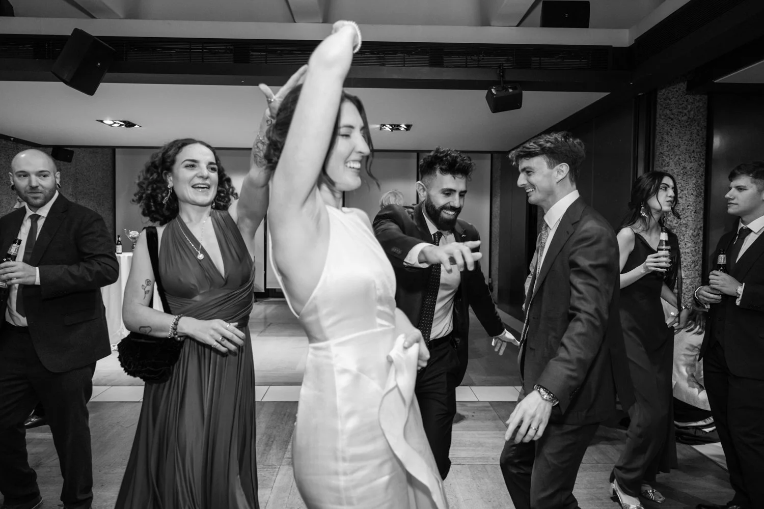 Bride spinning on the dance floor aided by her friend and the groom and mates dancing behind them.