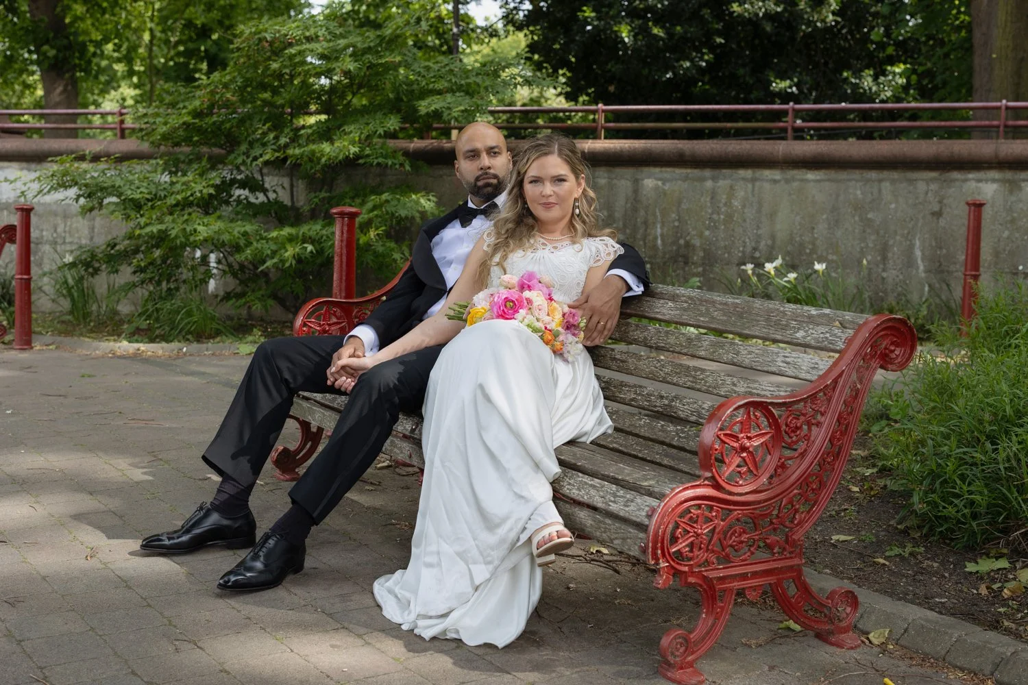 Bride and Groom lounging on a bench with red ironing arms.